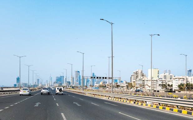 A highway with cars leads to a city skyline.