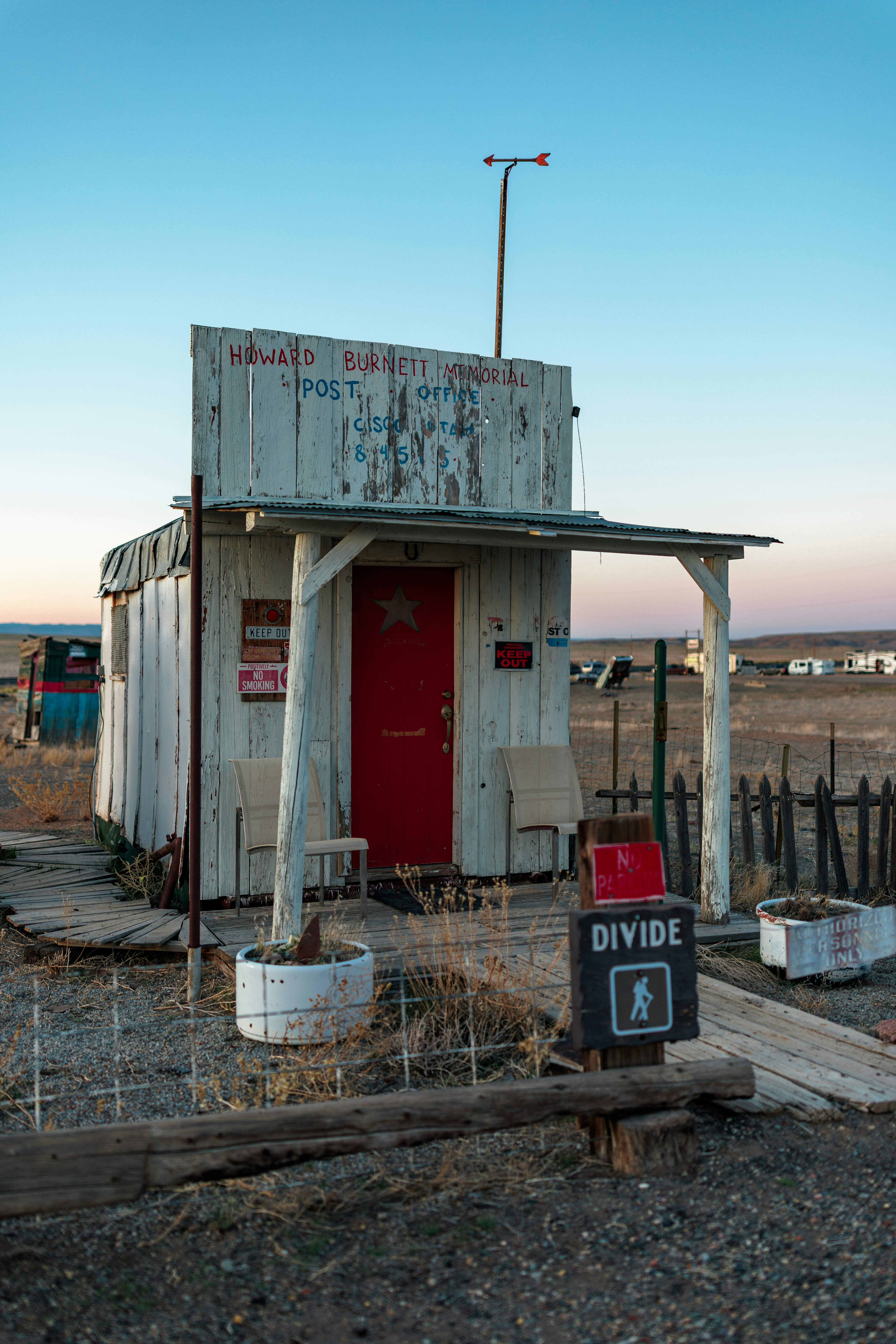 A weathered, small post office in a rural landscape.