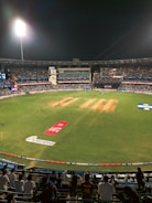 Cricket match happening at night under bright stadium lights.