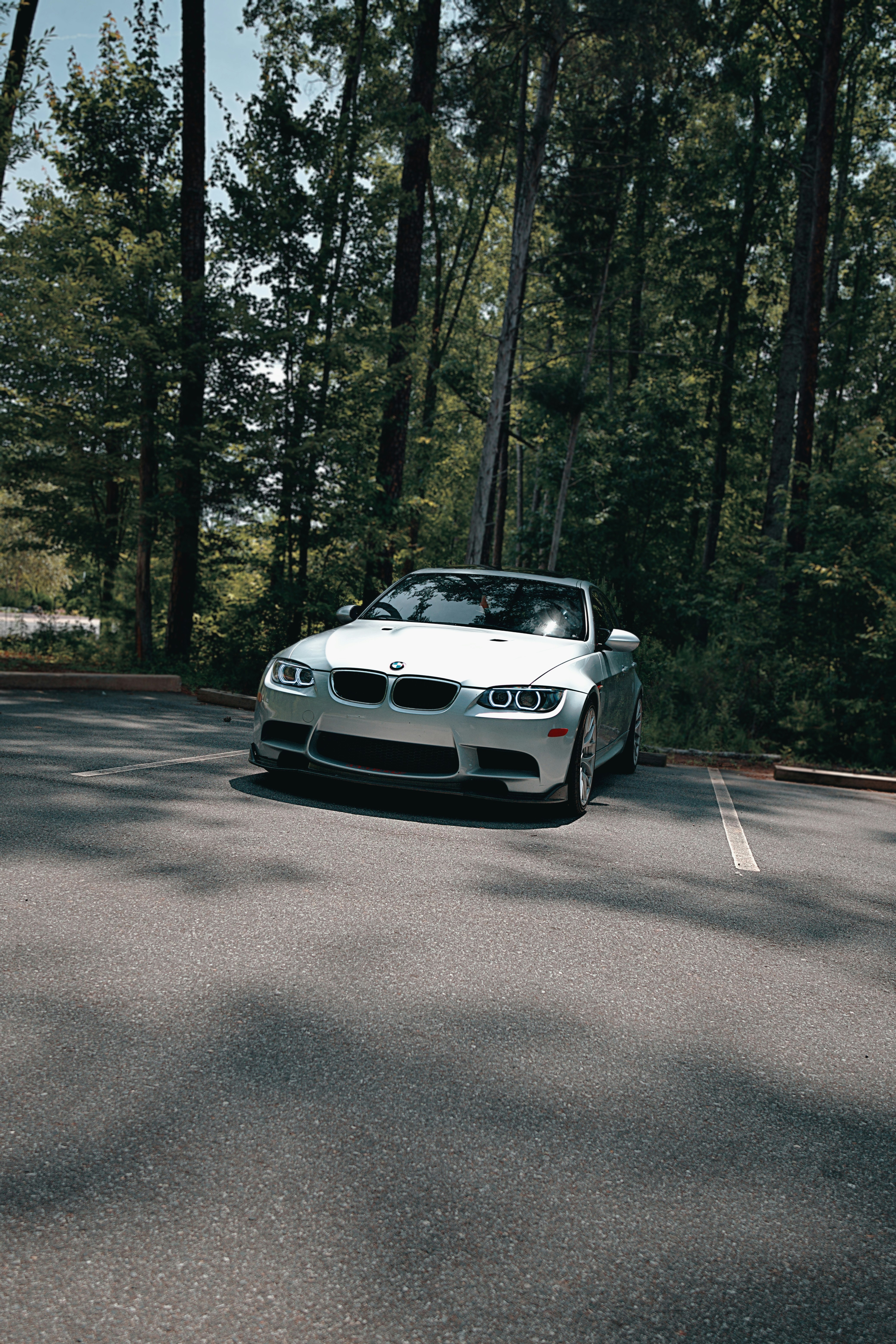 Una BMW decappottabile bianca è parcheggiata nel bosco.
