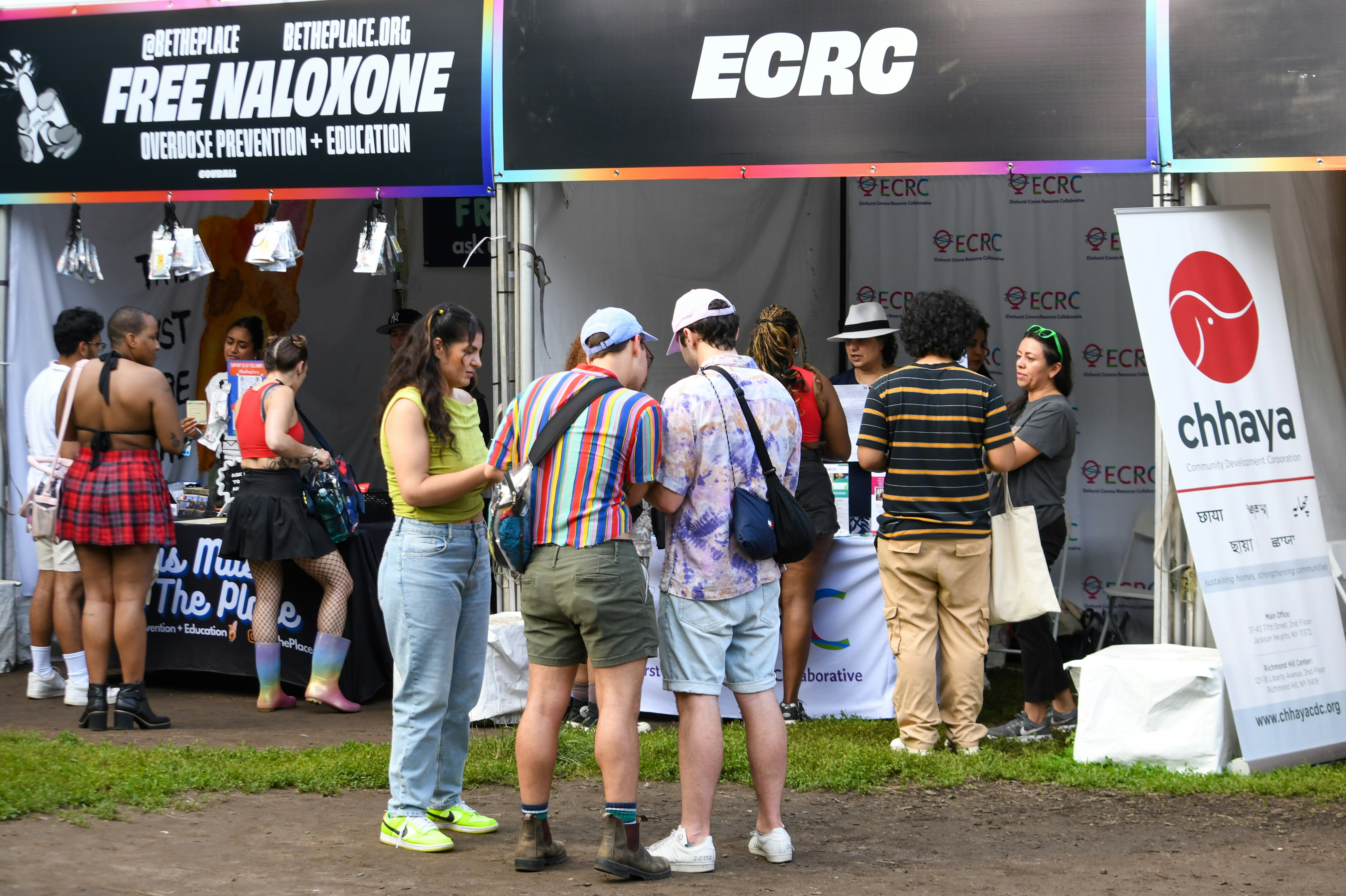 People interact at community organization booths during an outdoor public event.
