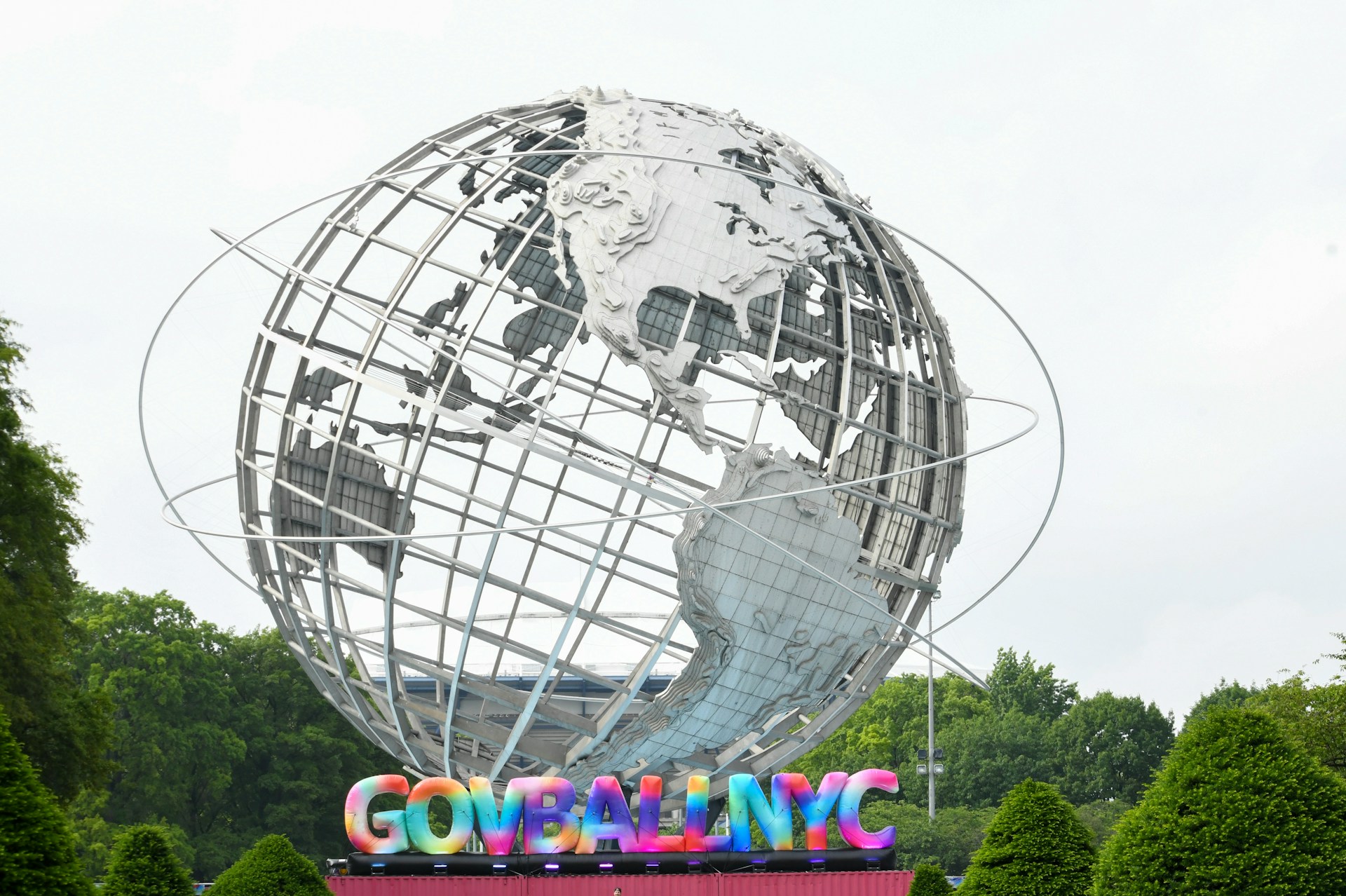 A giant metal globe stands against a cloudy sky.