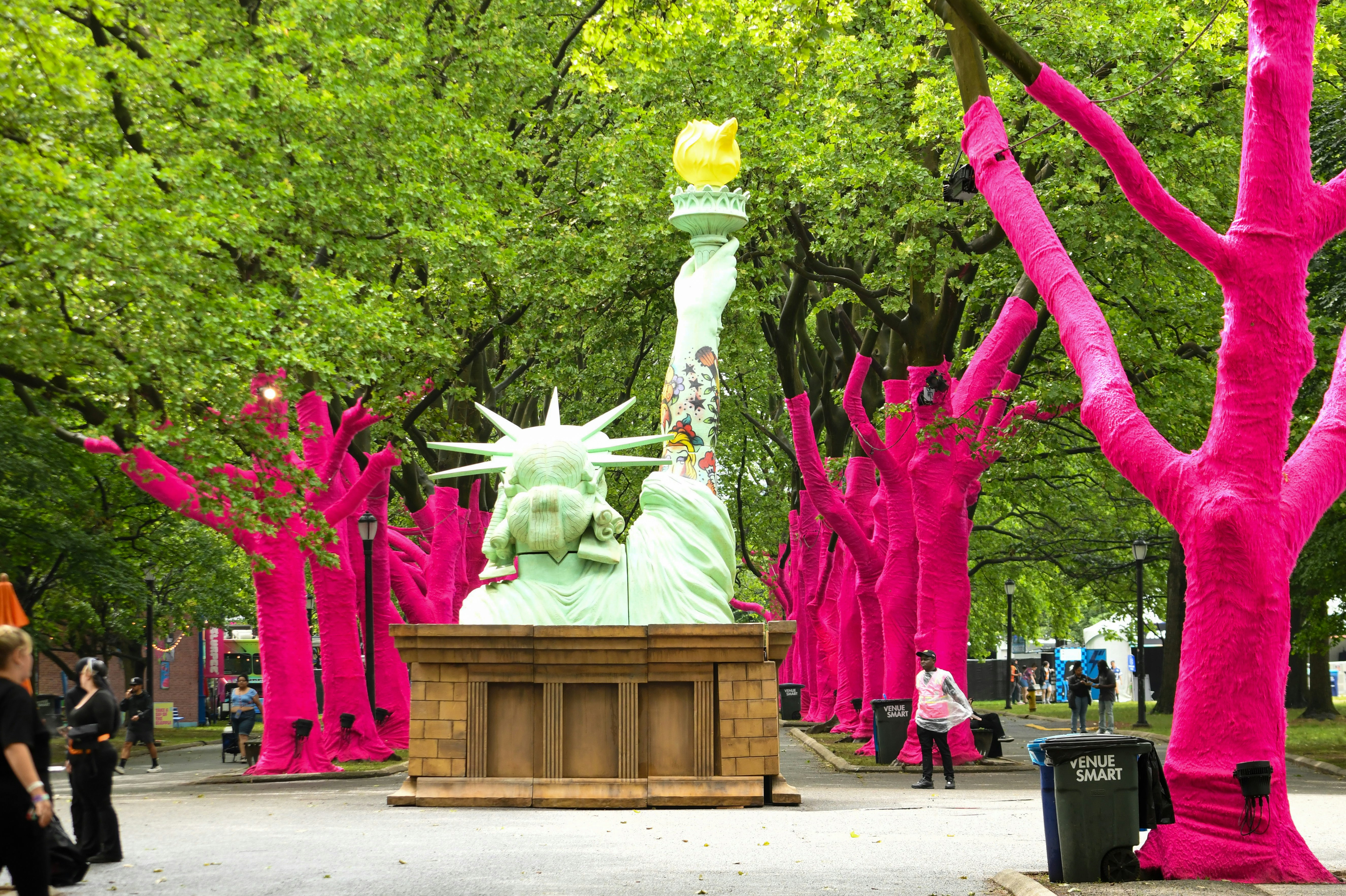 Statue of liberty and pink-wrapped trees in a park.