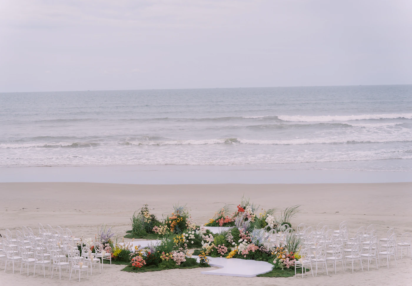Couple in elopement attire at a completely isolated Colombian Pacific beach with unbroken rainforest covering the hills around them