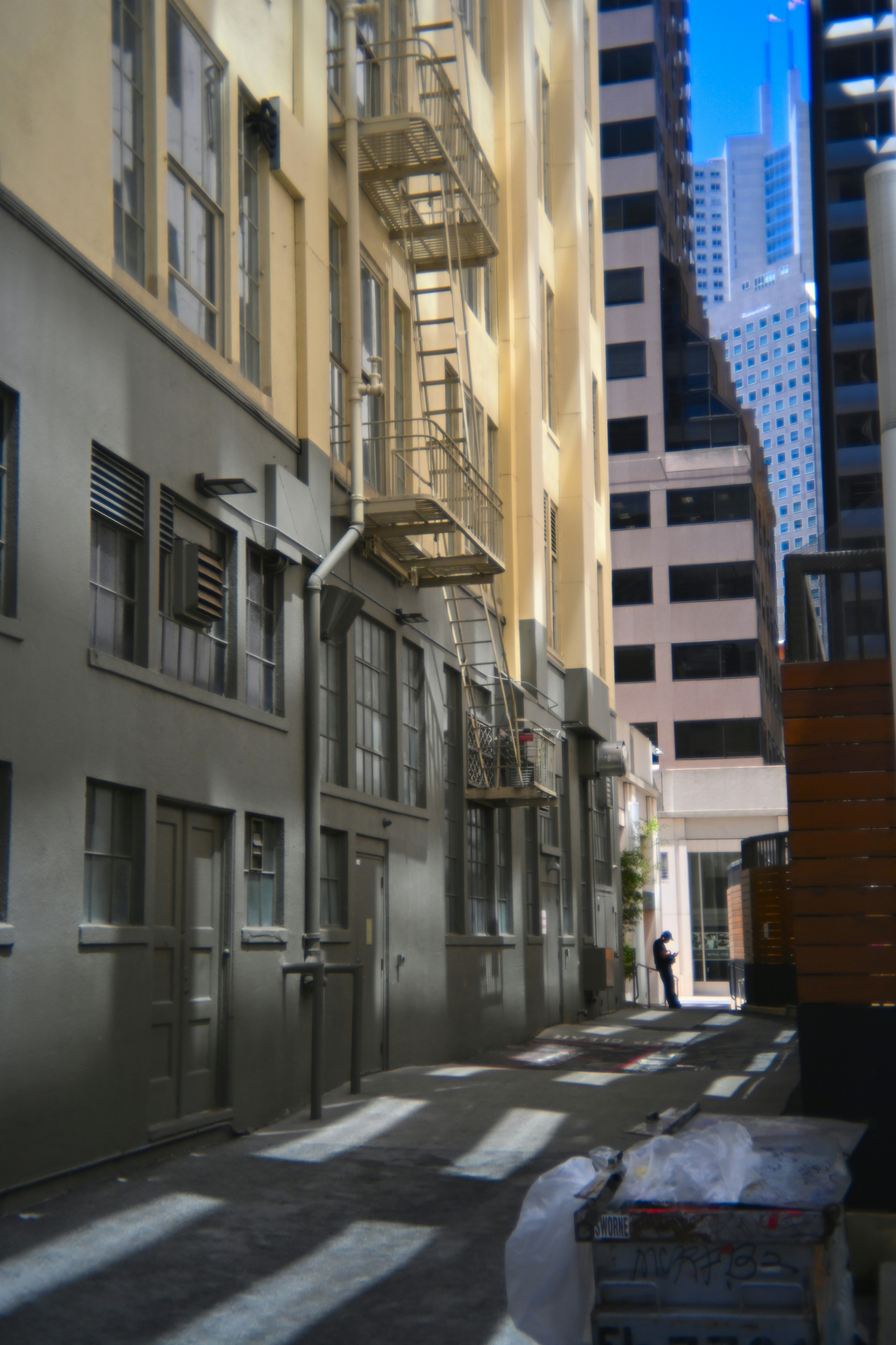 An alleyway with sunlight between tall buildings.