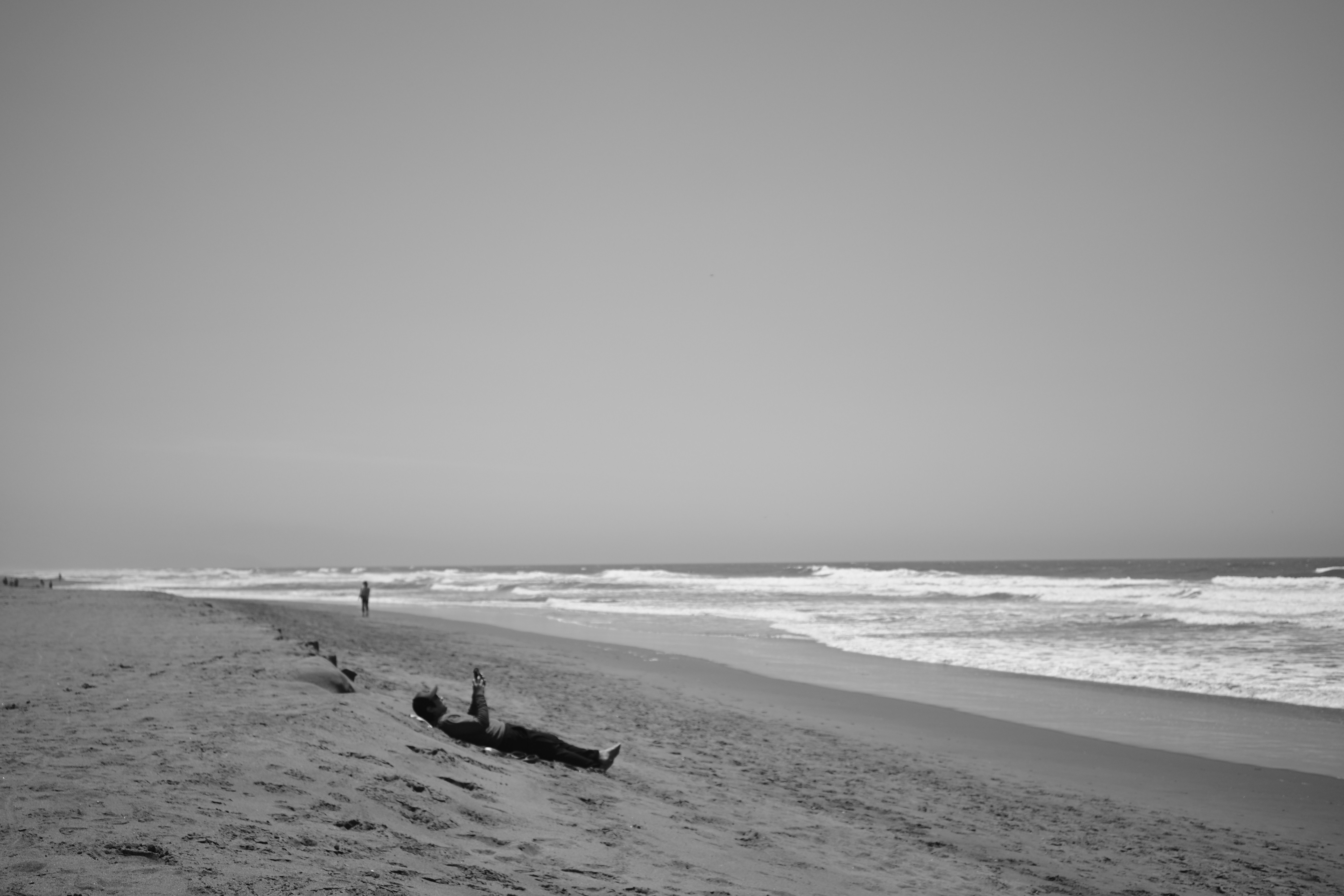 A person relaxes on a sandy beach by the ocean.