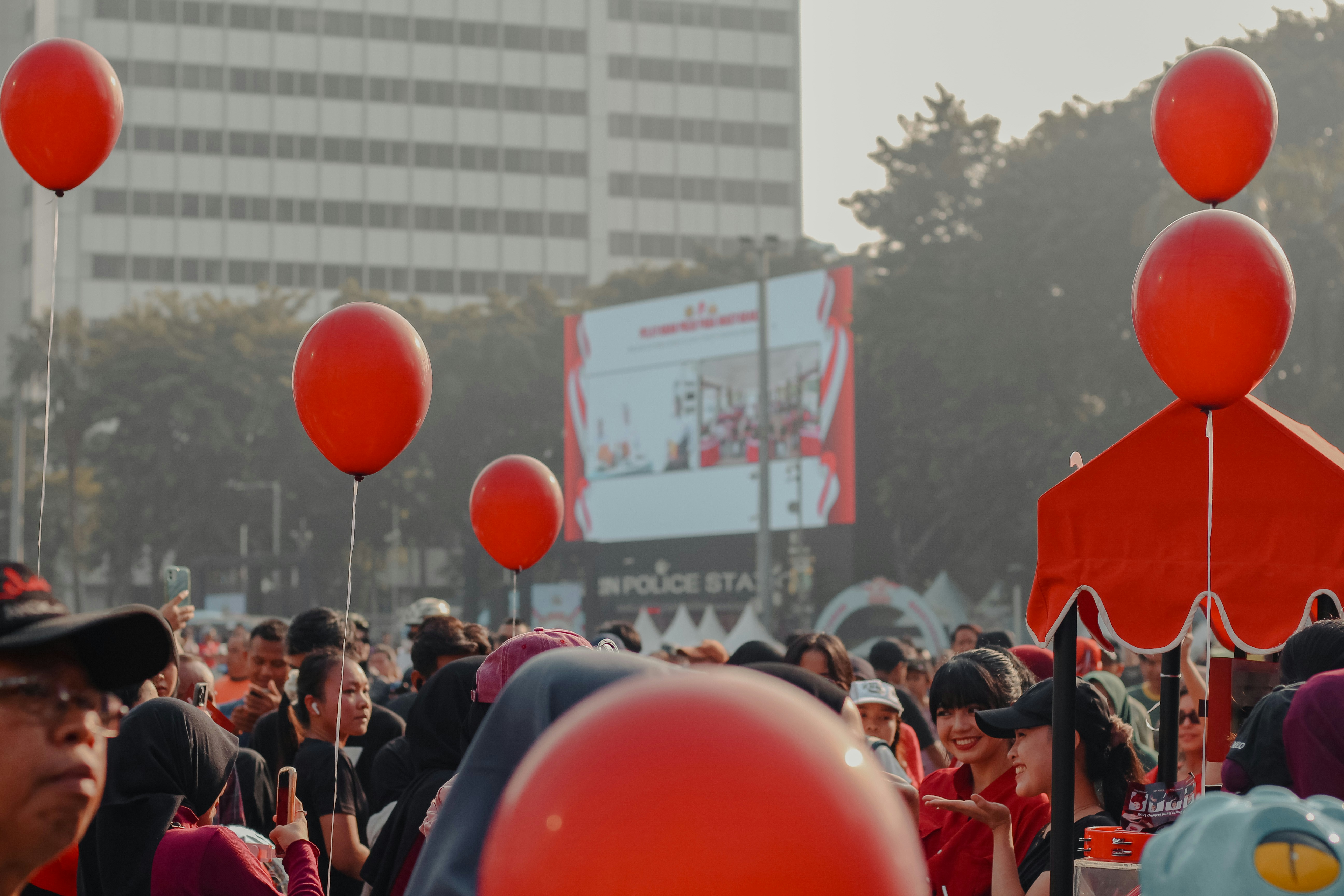 Balon merah melayang di atas kerumunan yang bersorak.