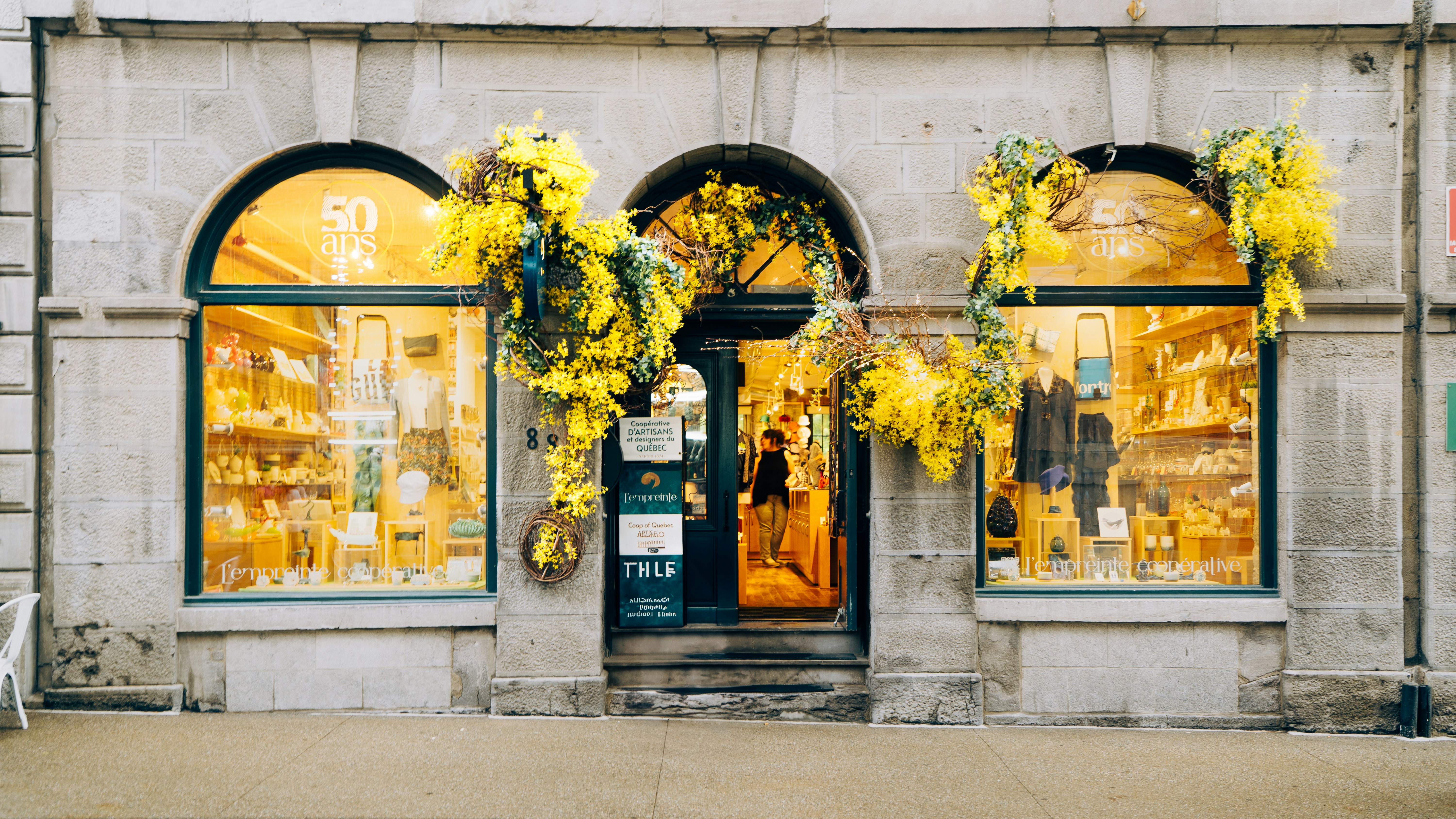 Yellow floral garlands decorate the stone storefront of a boutique.