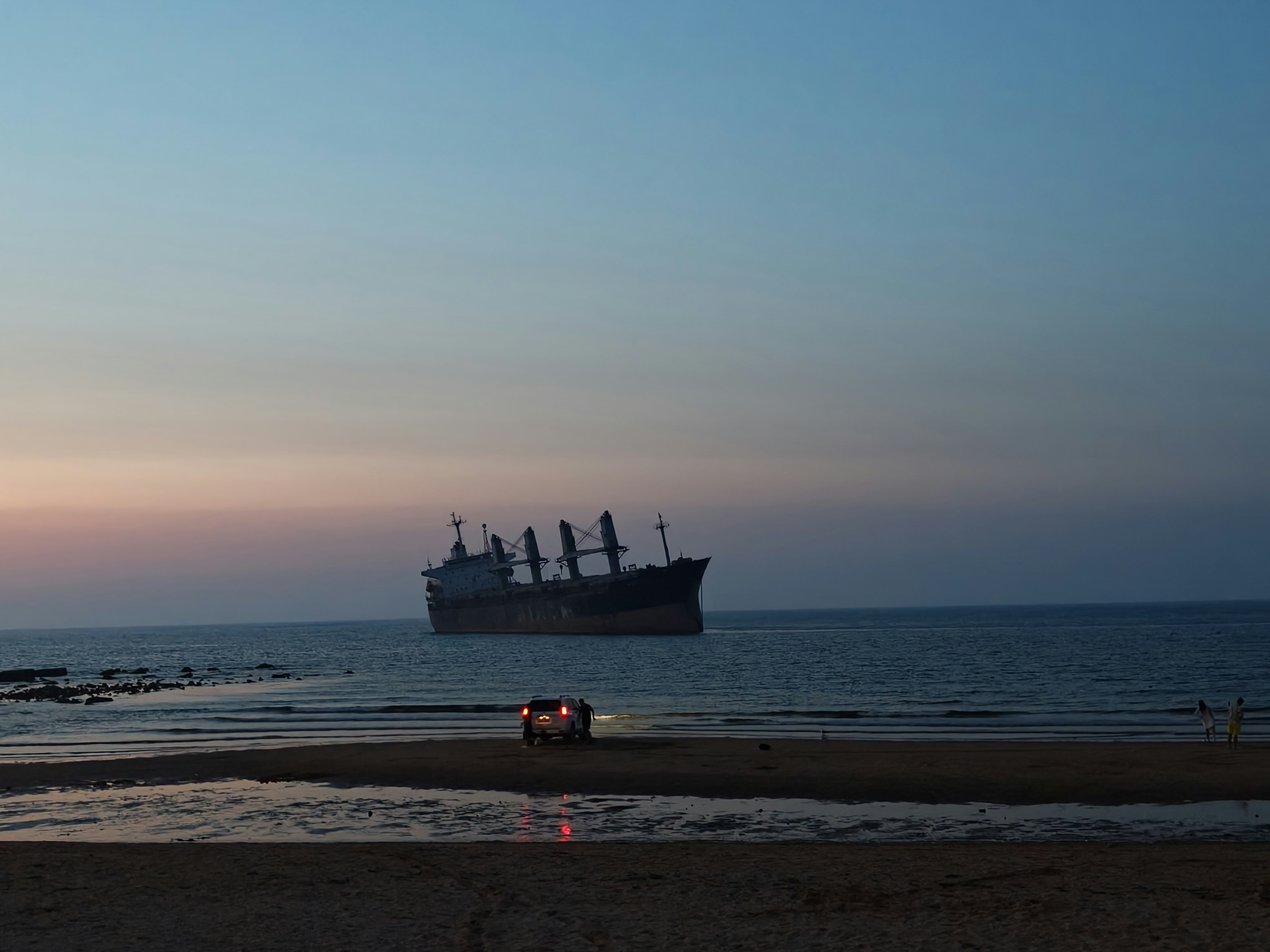 A large ship sits on the calm ocean at dusk.