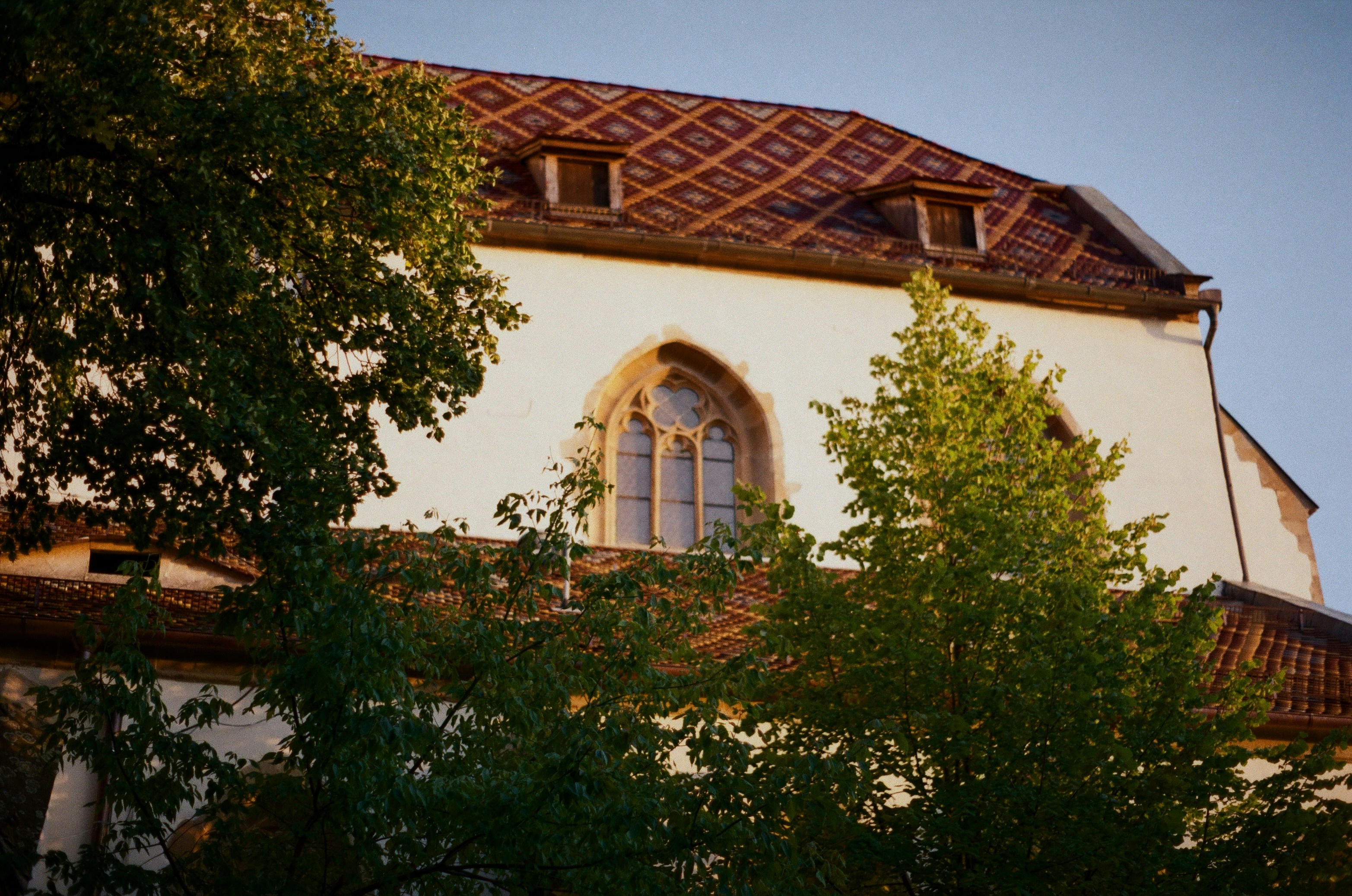 Church building partially obscured by trees.