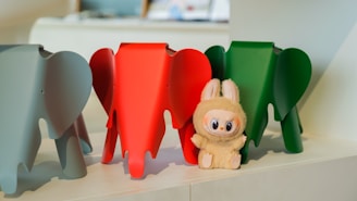 Three colorful elephants and a bunny stand together.