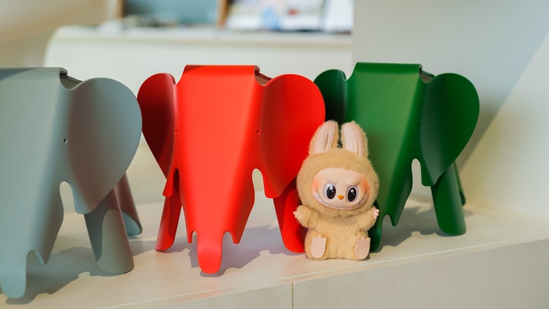 Three colorful elephants and a bunny stand together.