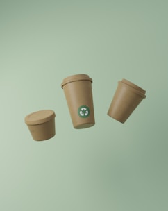 Three recyclable coffee cups floating on a green background.