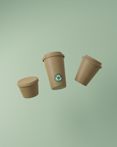 Three recyclable coffee cups floating on a green background.