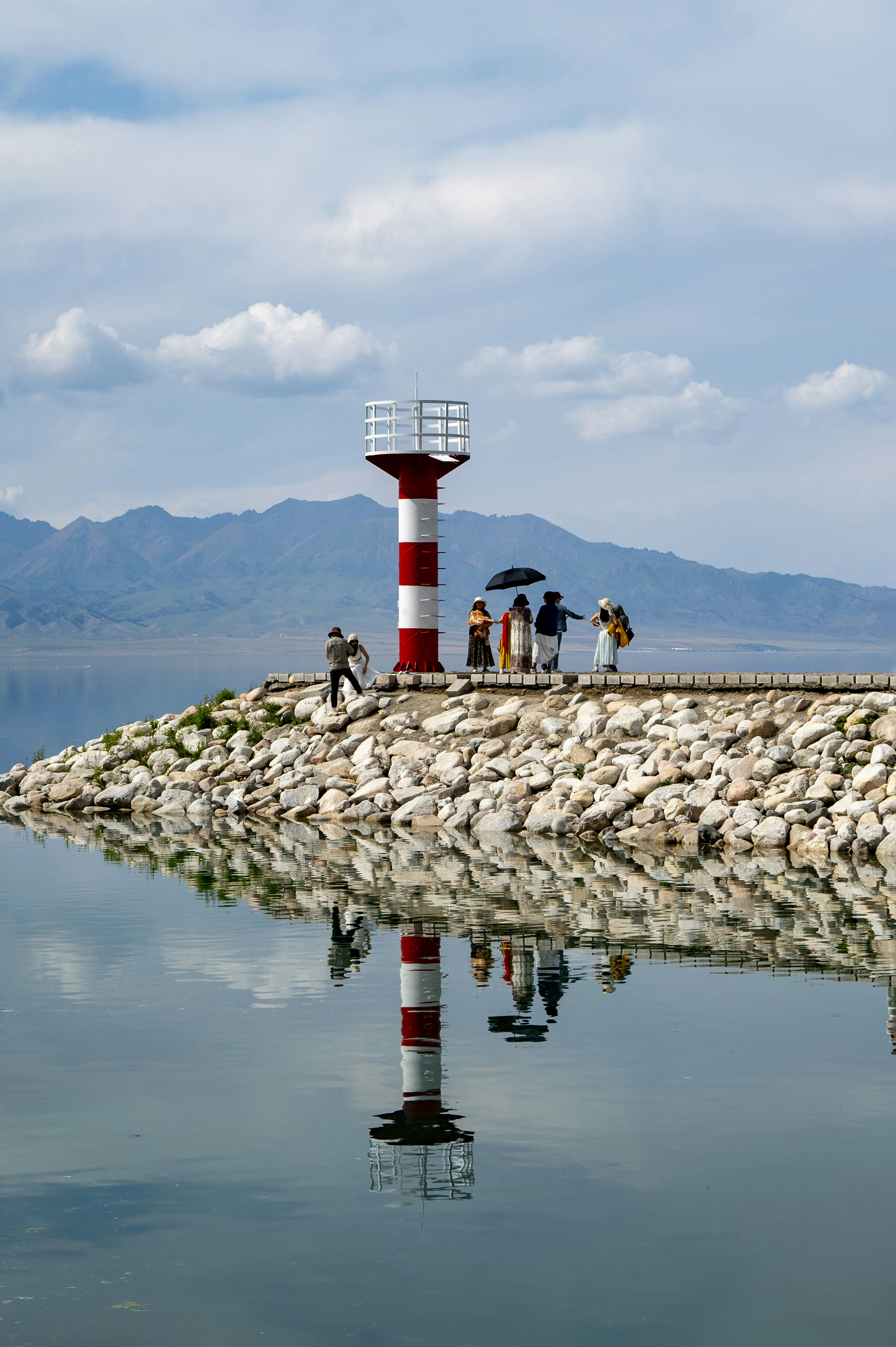 Lighthouse stands on a pier with people and reflection. photo – Free ...