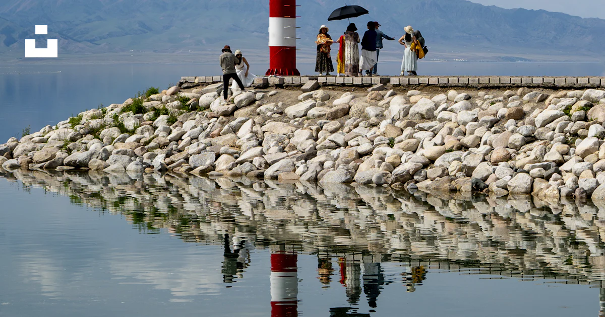 Lighthouse stands on a pier with people and reflection. photo – Free ...