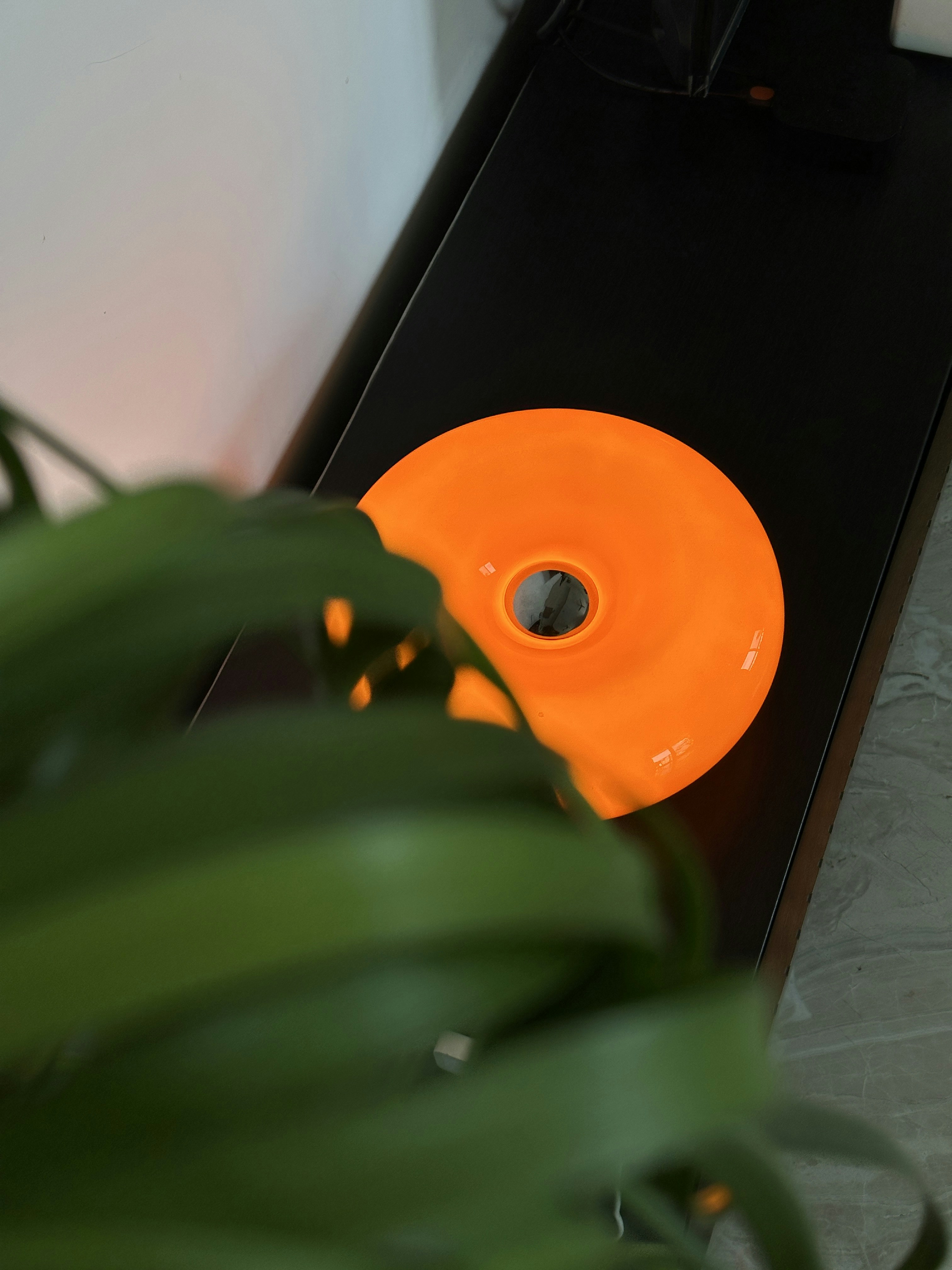 An orange disc sits on a dark surface.