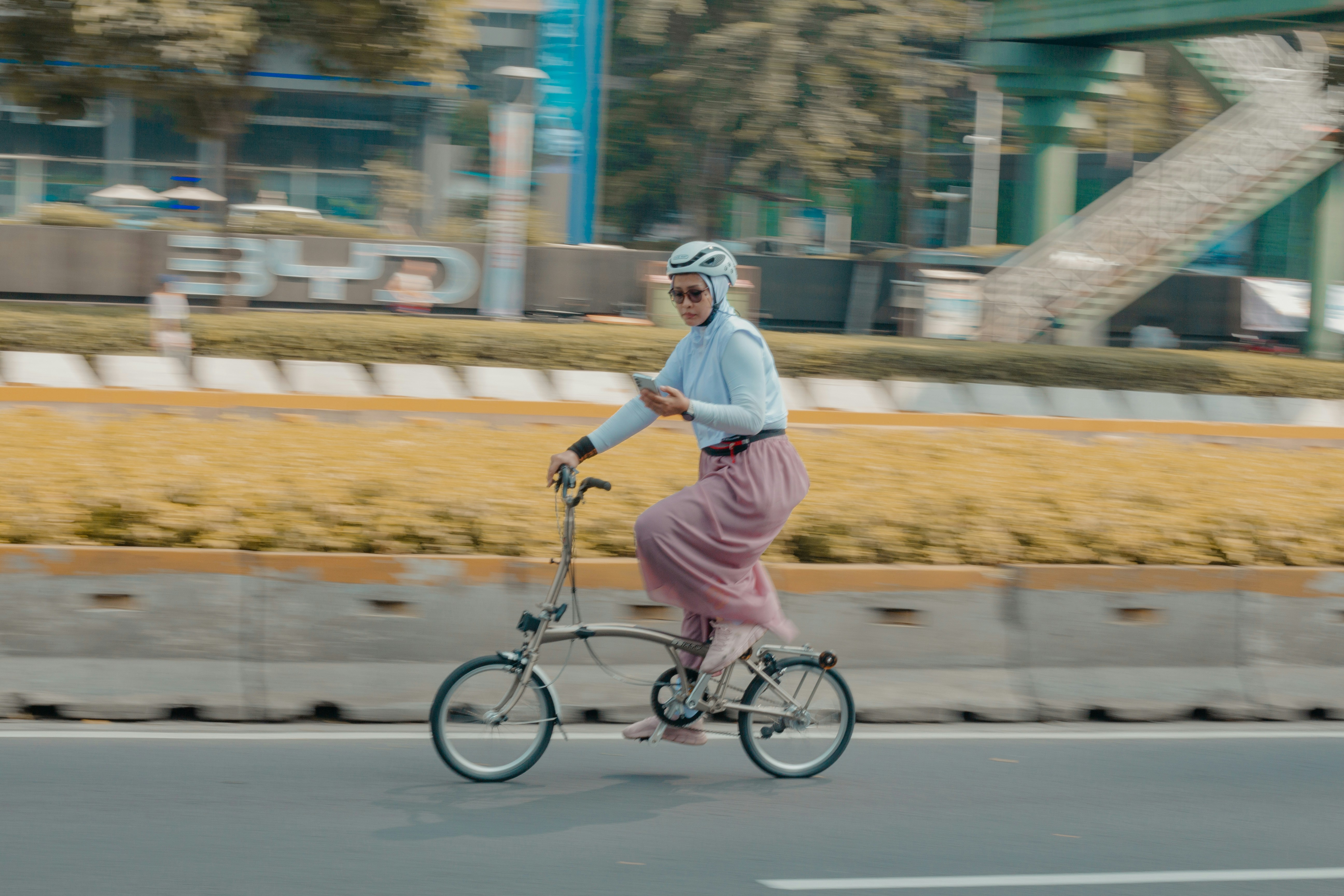 Woman bikes while checking her phone.