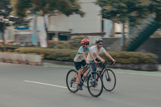 Two cyclists are riding bikes on a road.