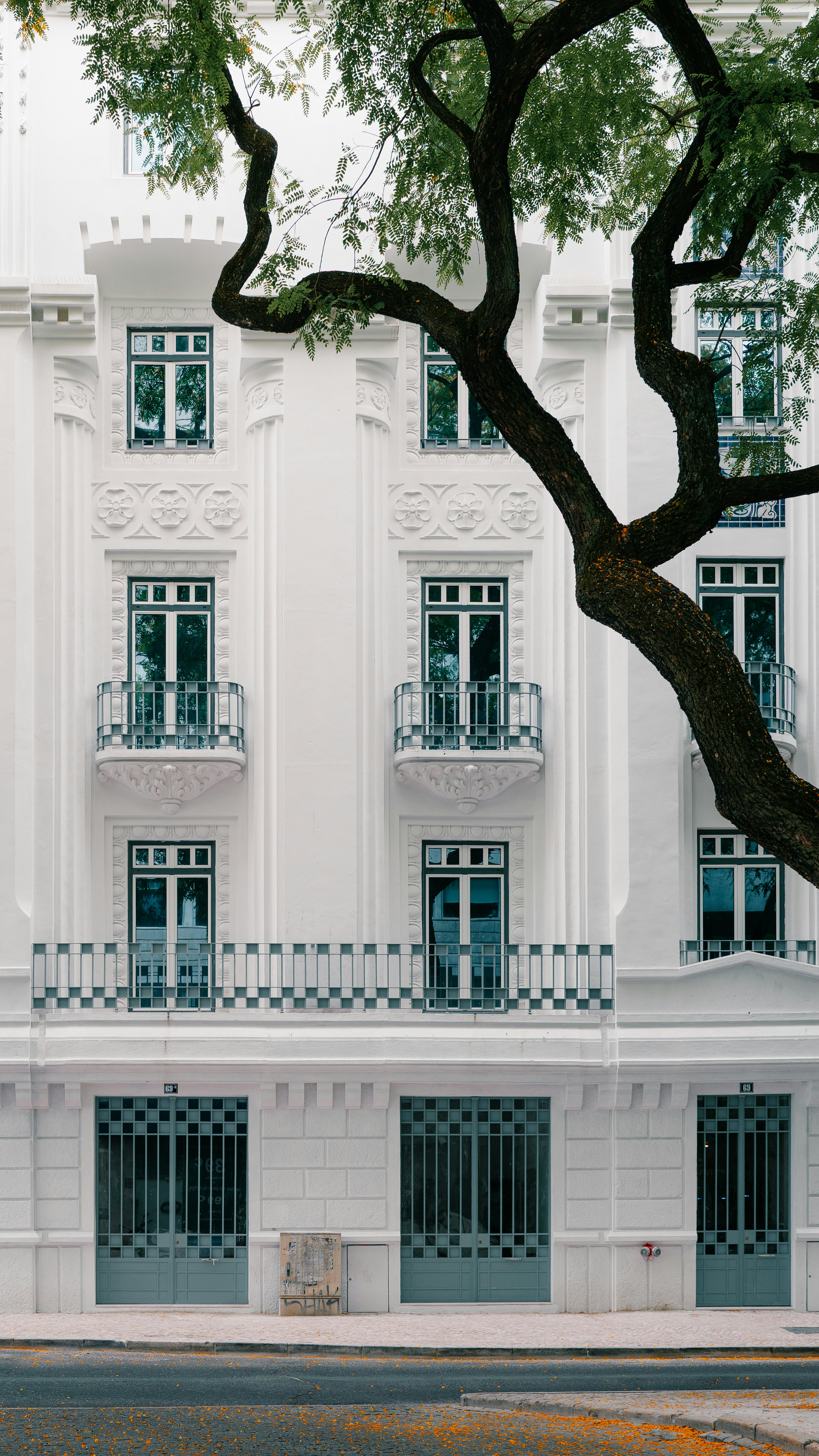 白い建物を囲む木々とバルコニー。