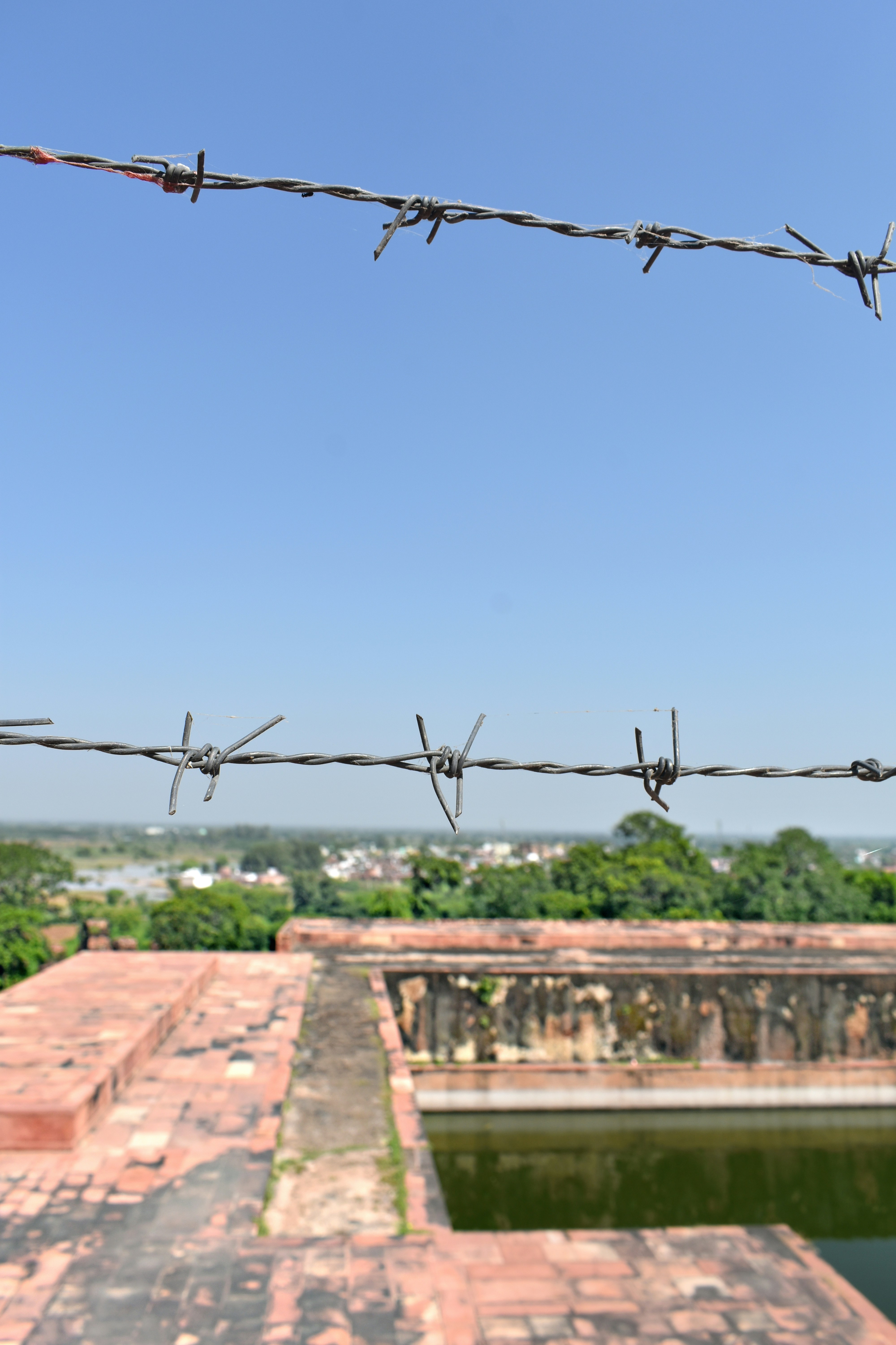 Barbed wire over a building's water feature.