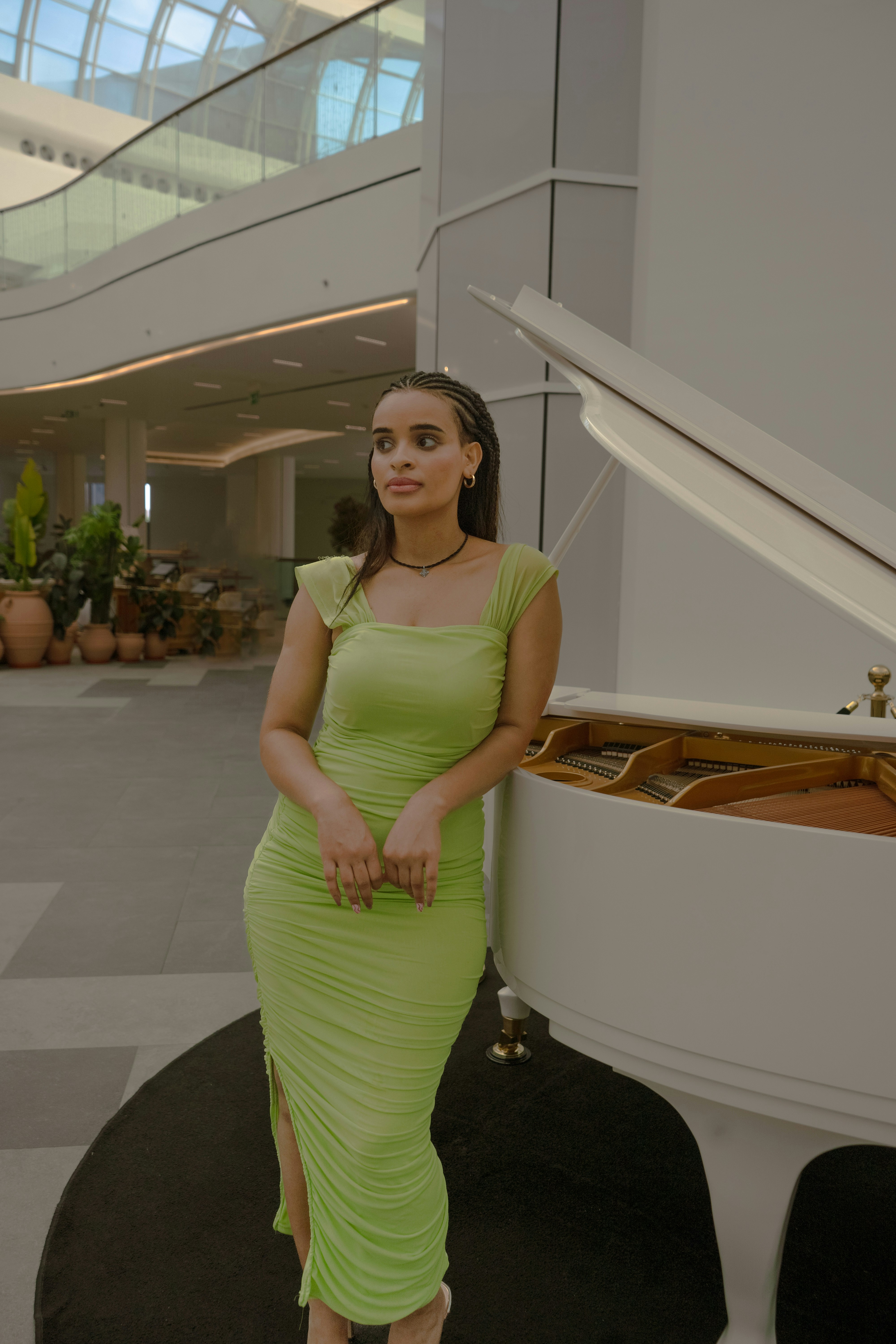 A woman poses beside a white piano.