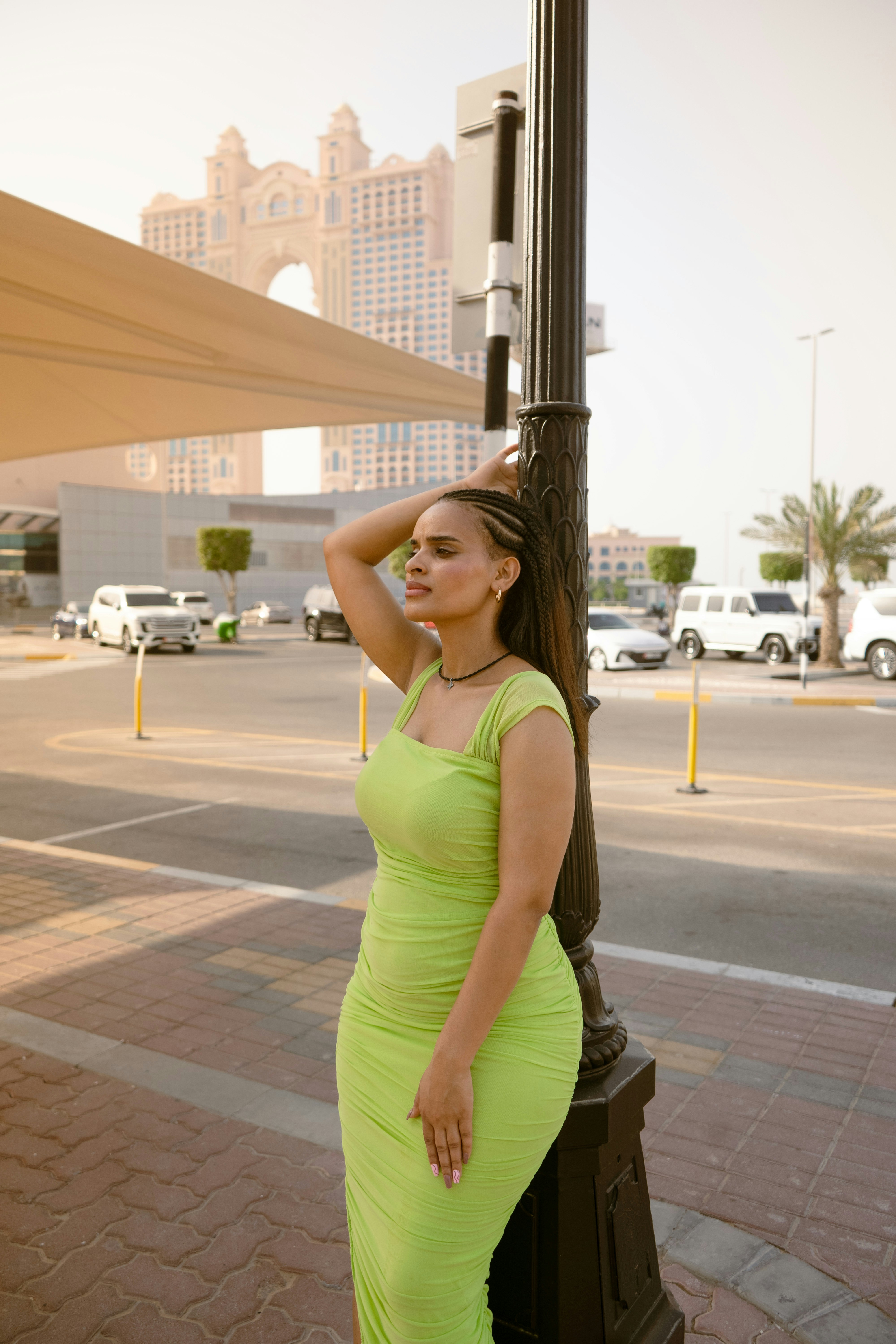 Woman poses in a green dress near a light post.