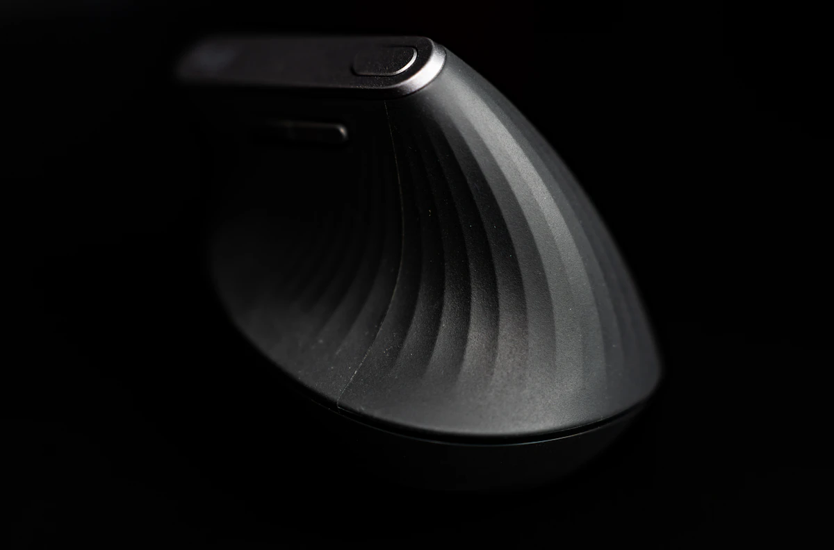 Curved ergonomic computer mouse on a dark desk mat