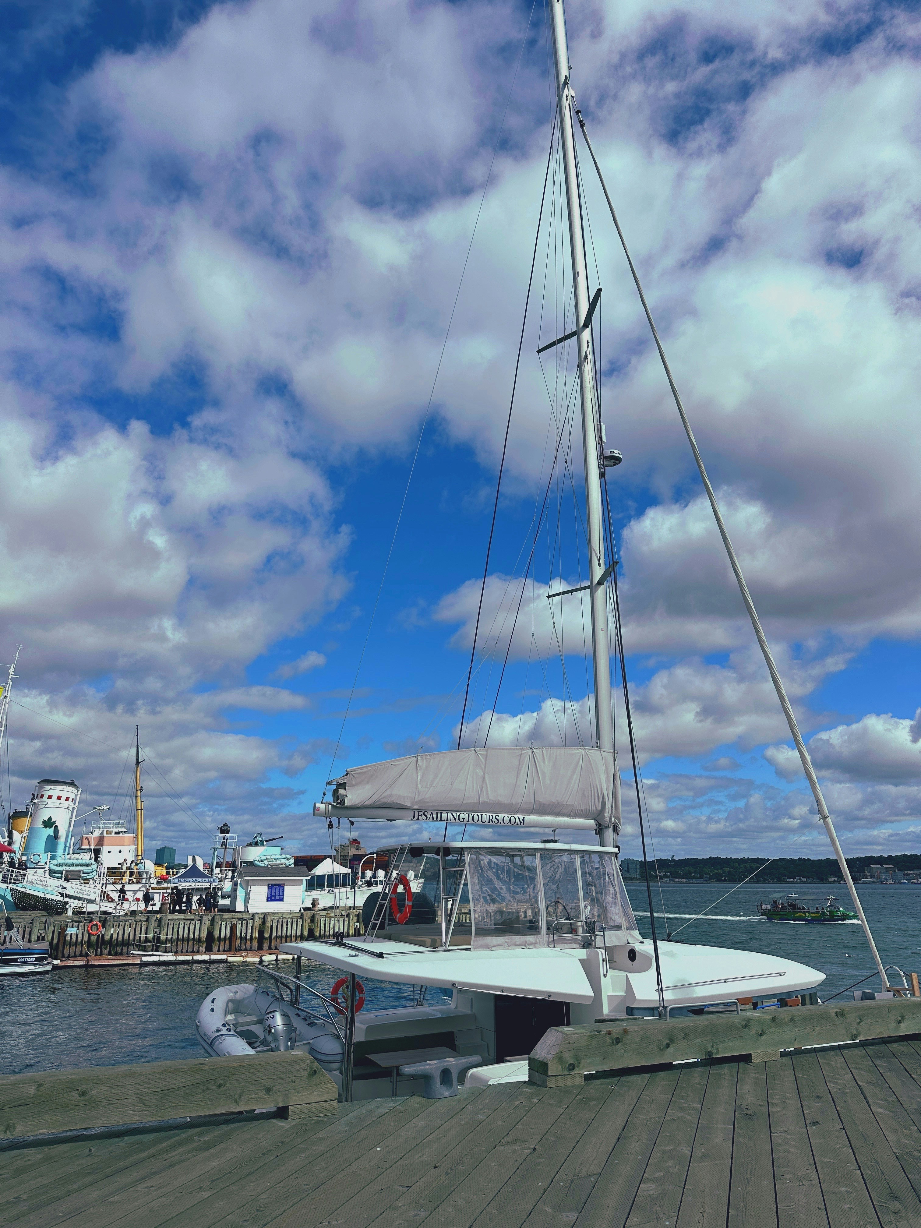 A sailboat is docked under a beautiful, cloudy sky.