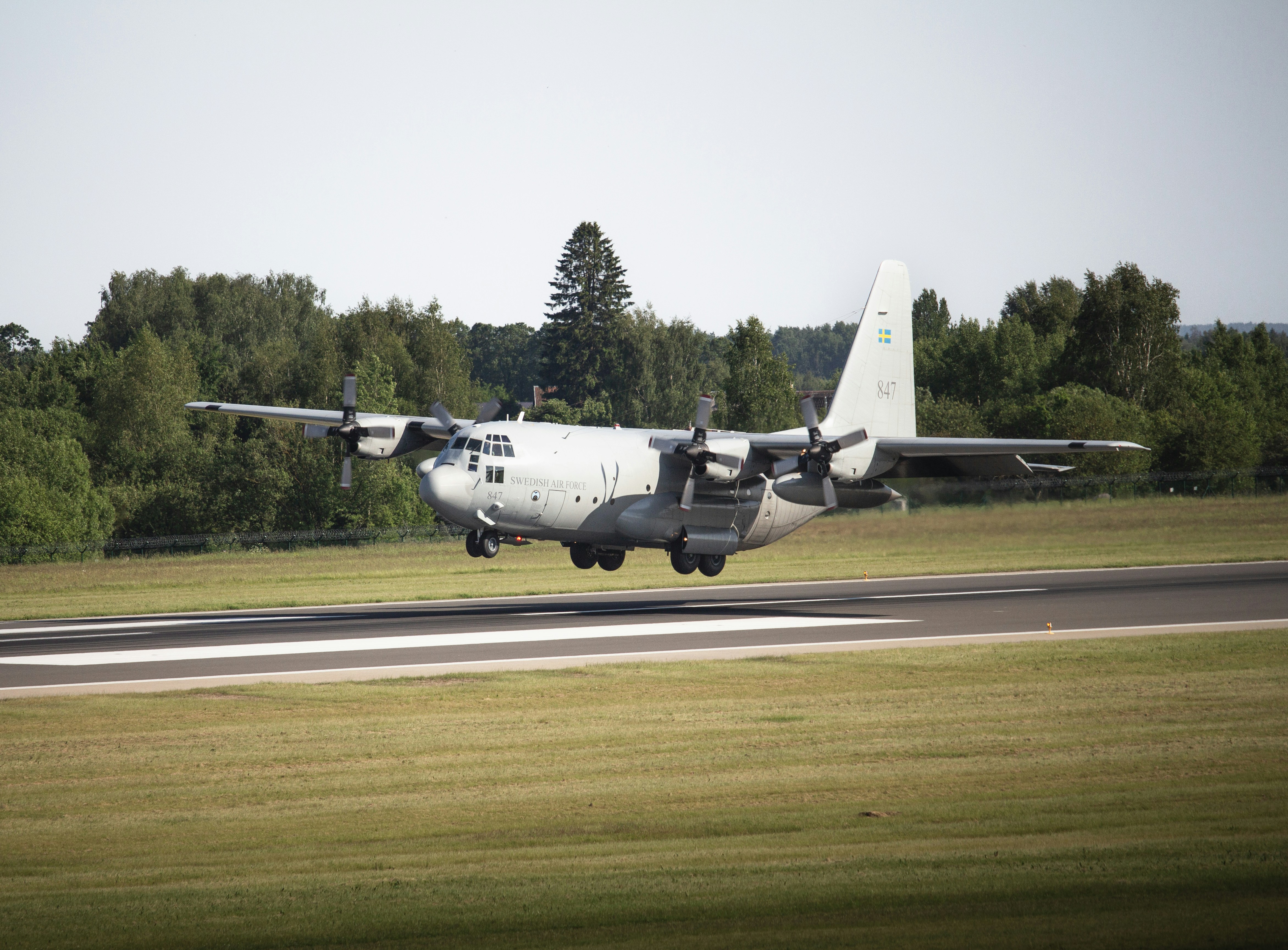 A c-130 military aircraft lands on a runway.