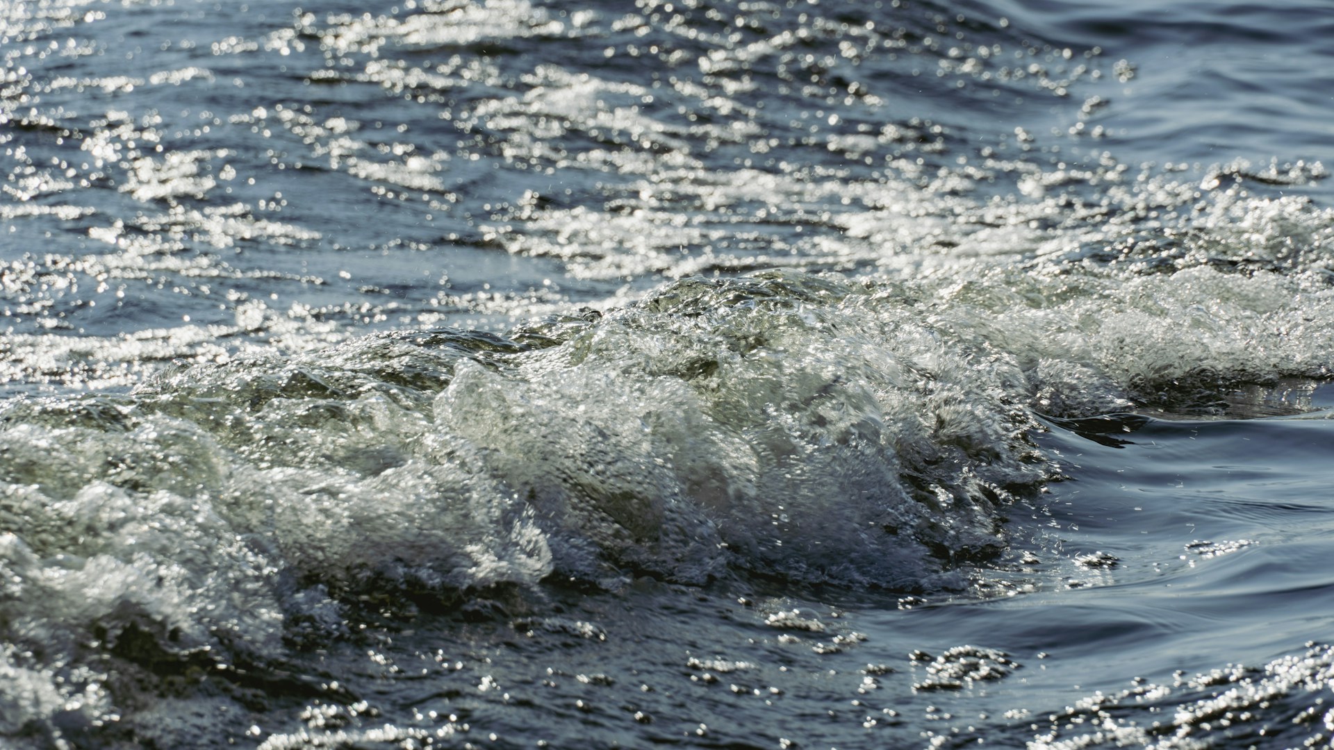 Waves are crashing in the sparkling blue water.