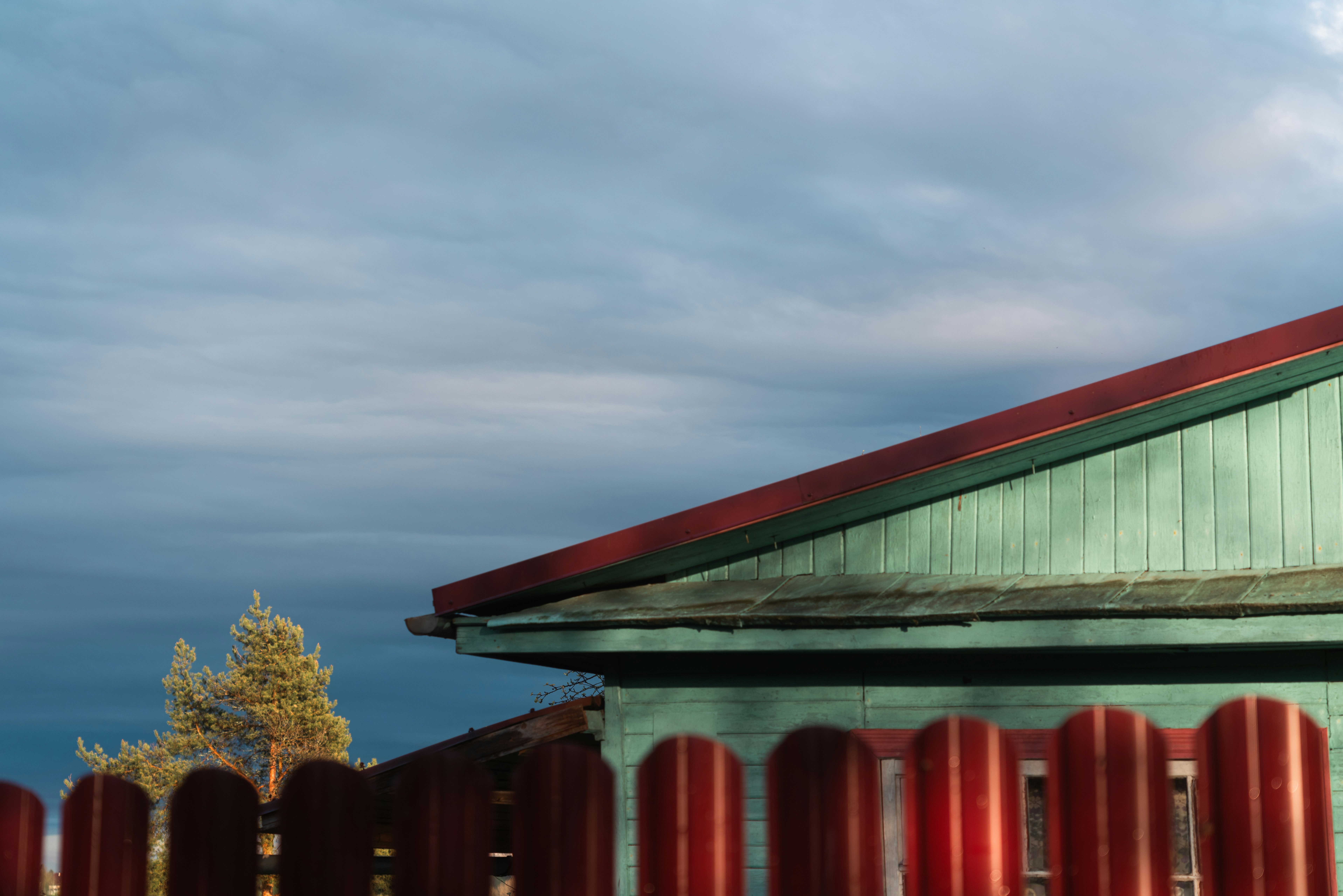 Une maison et une clôture sous un ciel nuageux.