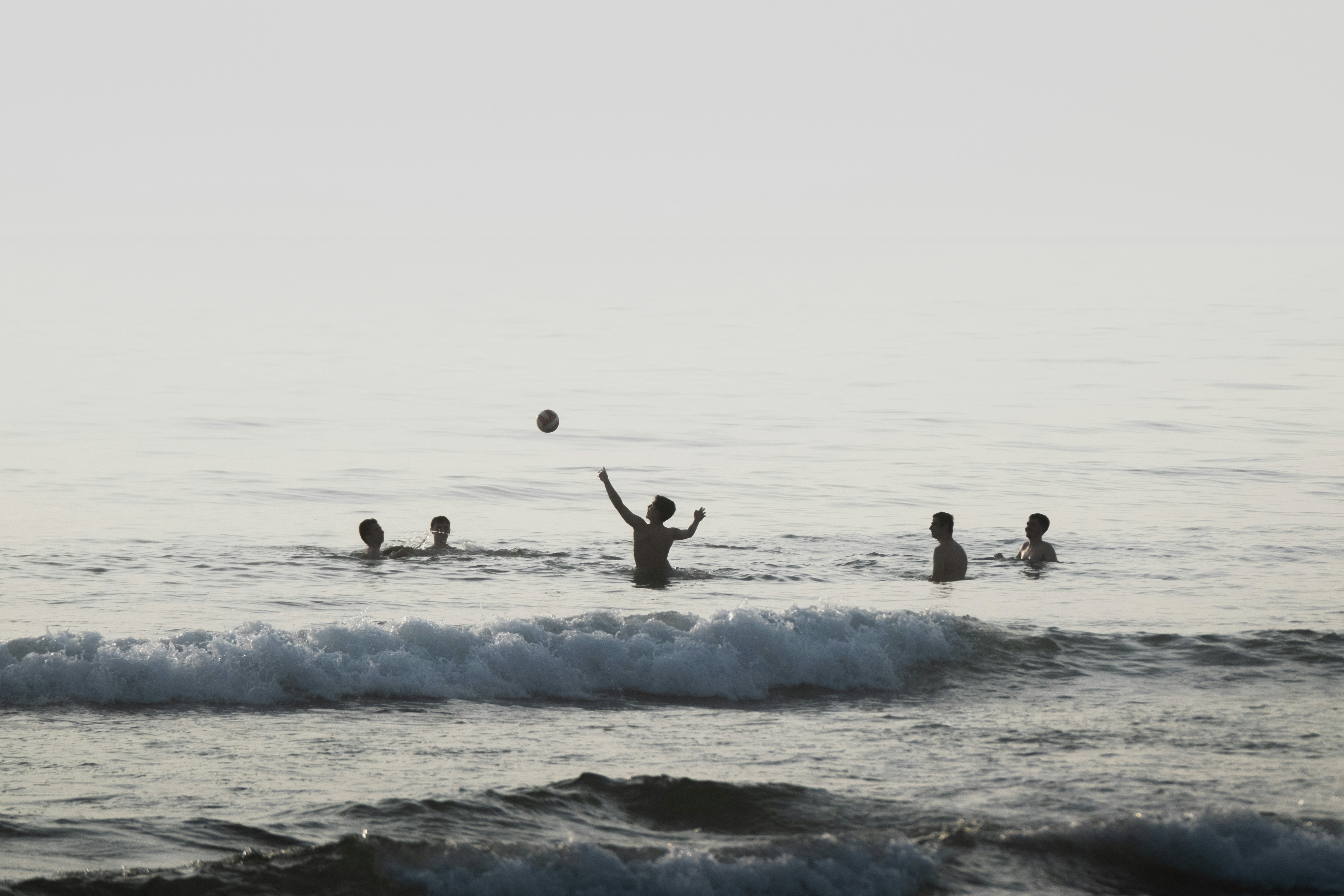 People play ball in the ocean water.