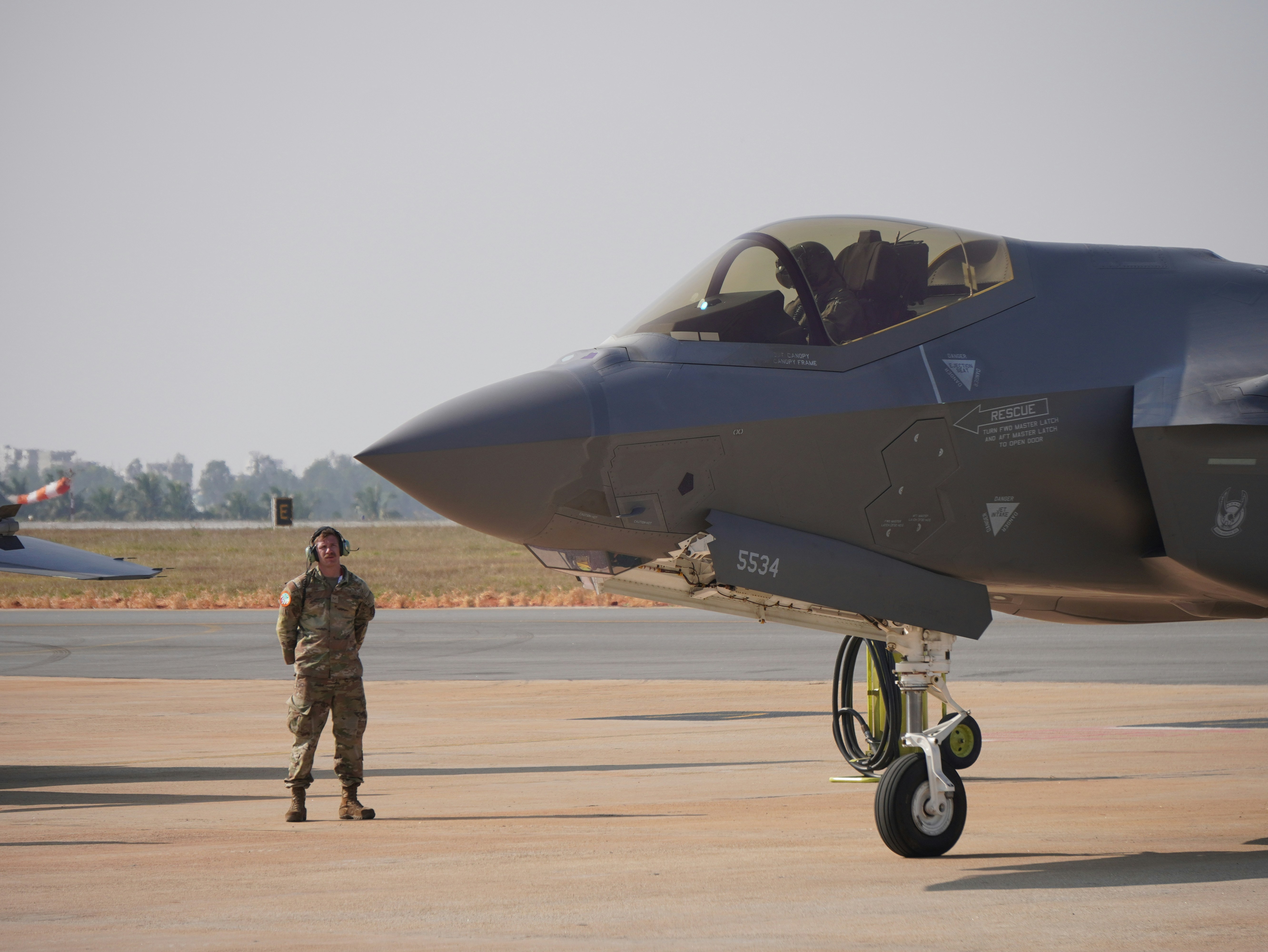 A fighter jet sits beside an air force pilot.