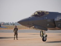 A fighter jet sits beside an air force pilot.
