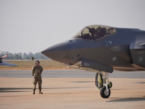 A fighter jet sits beside an air force pilot.