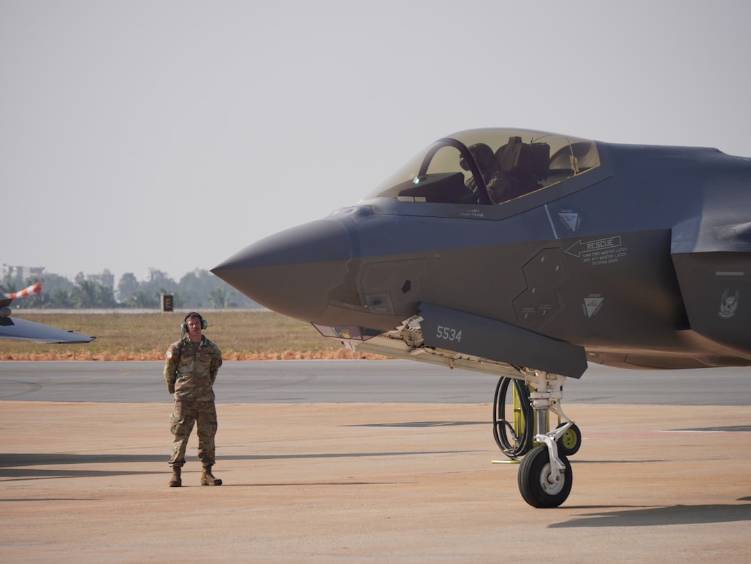A fighter jet sits beside an air force pilot.