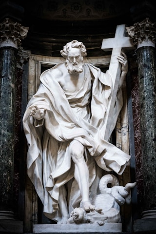 A marble statue of a man holding a cross.