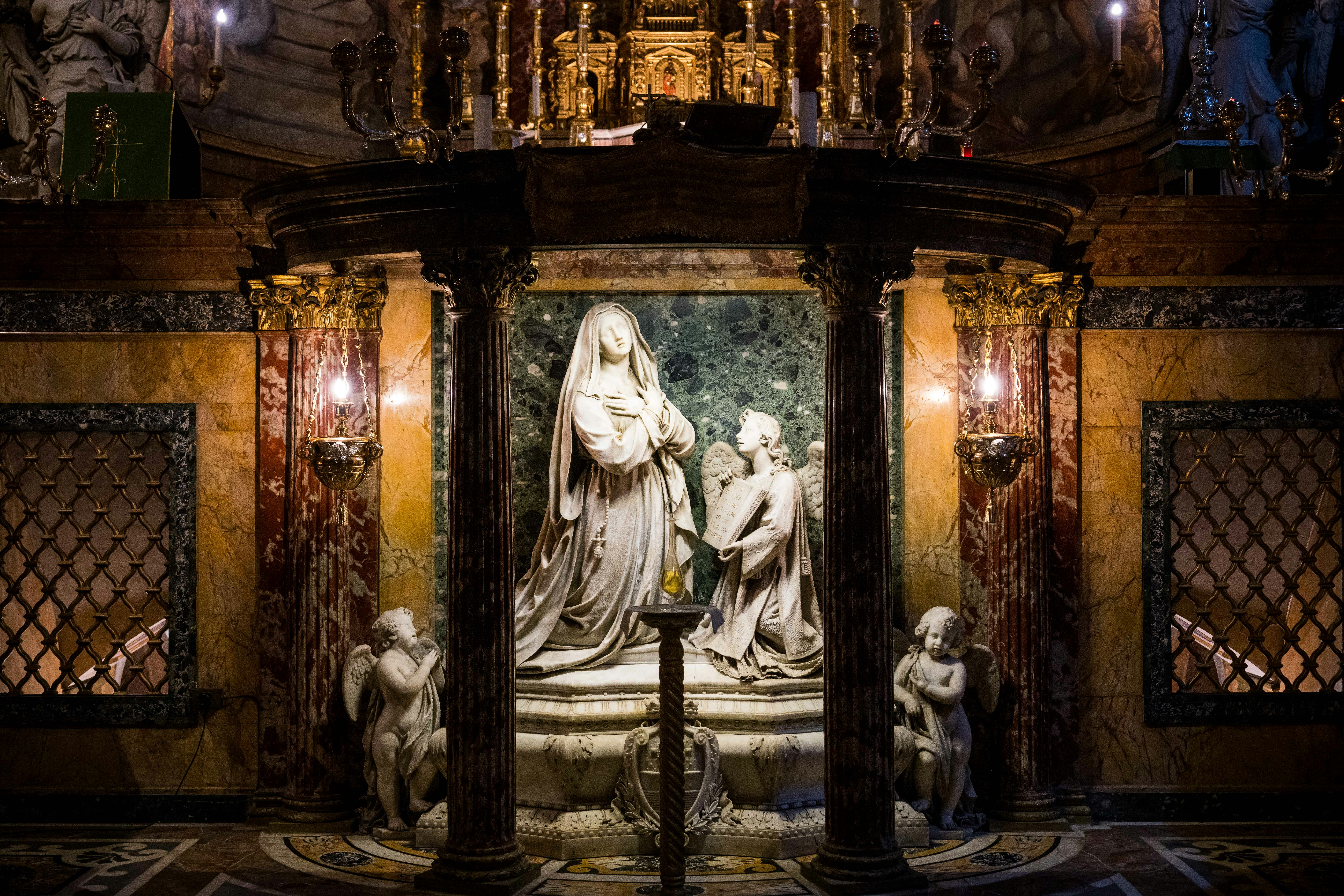 A marble sculpture is set inside a gilded shrine.