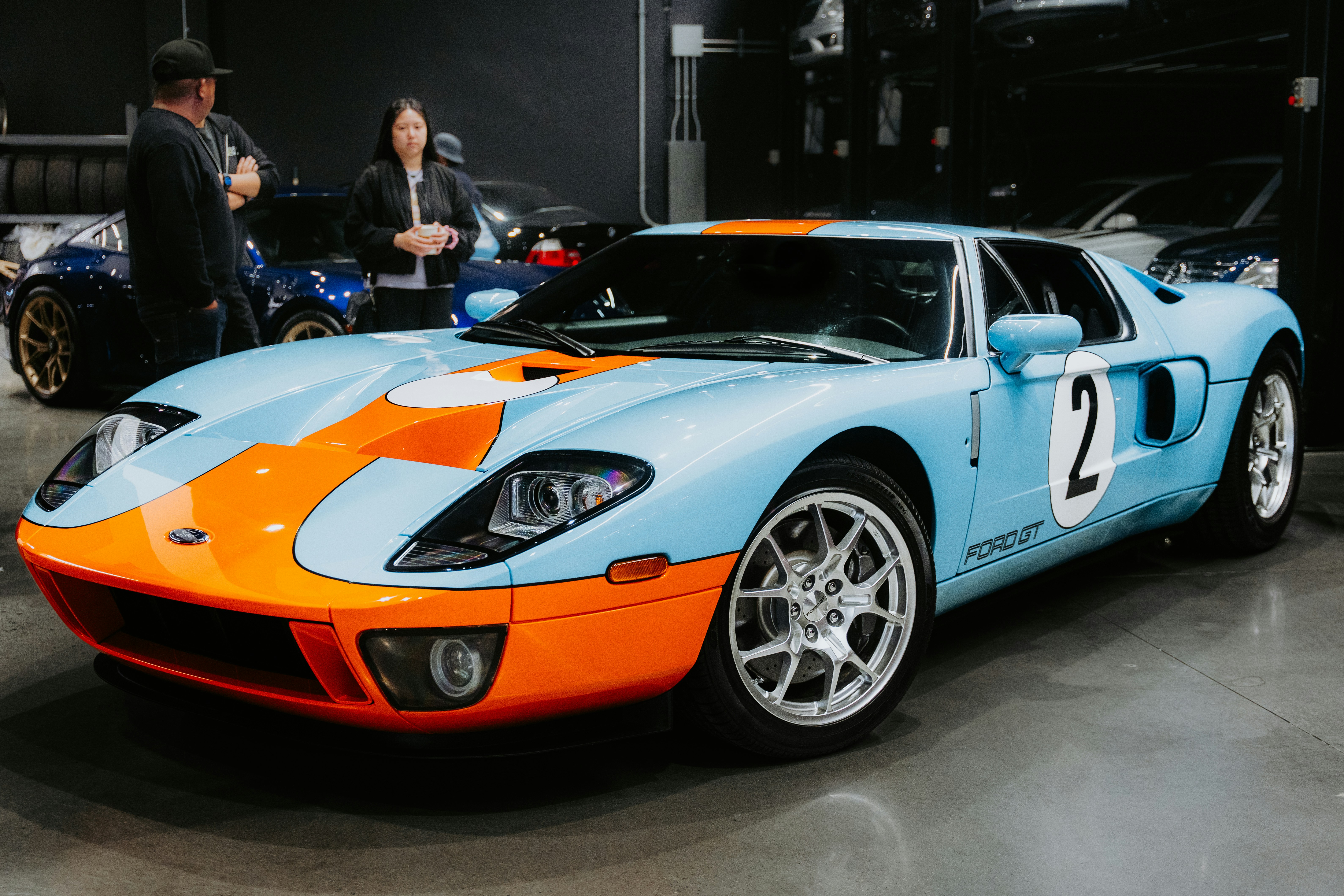 ショールームに展示されているブルーとオレンジのフォードGT。の写真