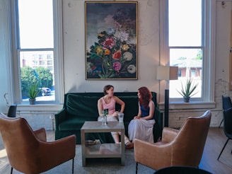 Two women are talking on a green couch.