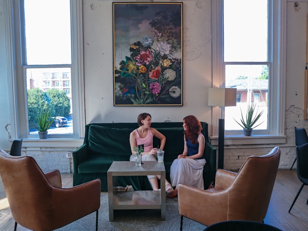 Two women are talking on a green couch.