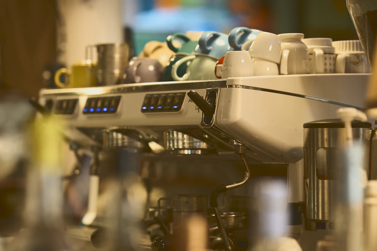 An espresso machine with cups stacked on top of it behind a cafe counter