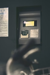 Atm with a hand blurry in the foreground.