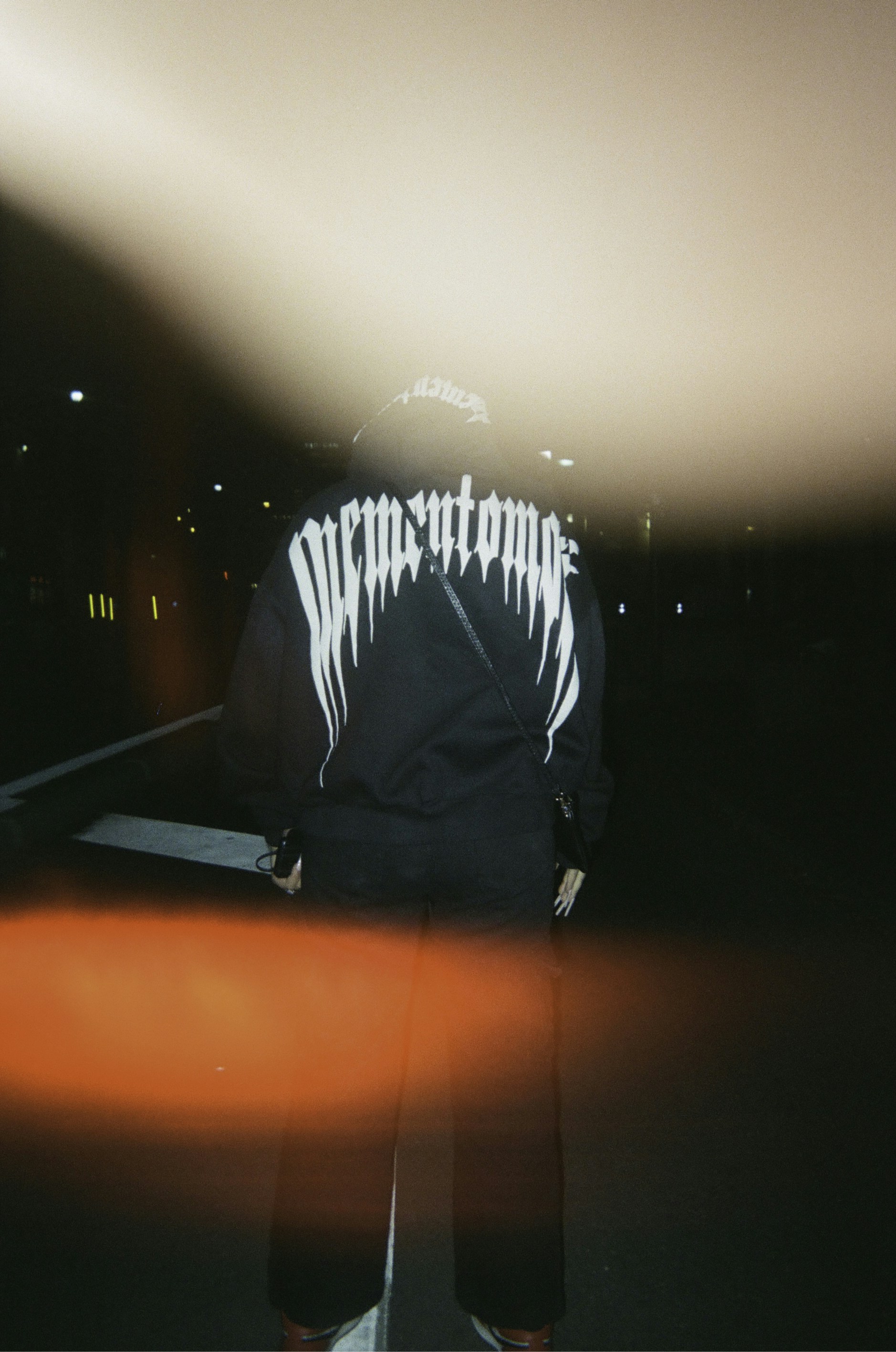 Person in black clothing stands in the dark.