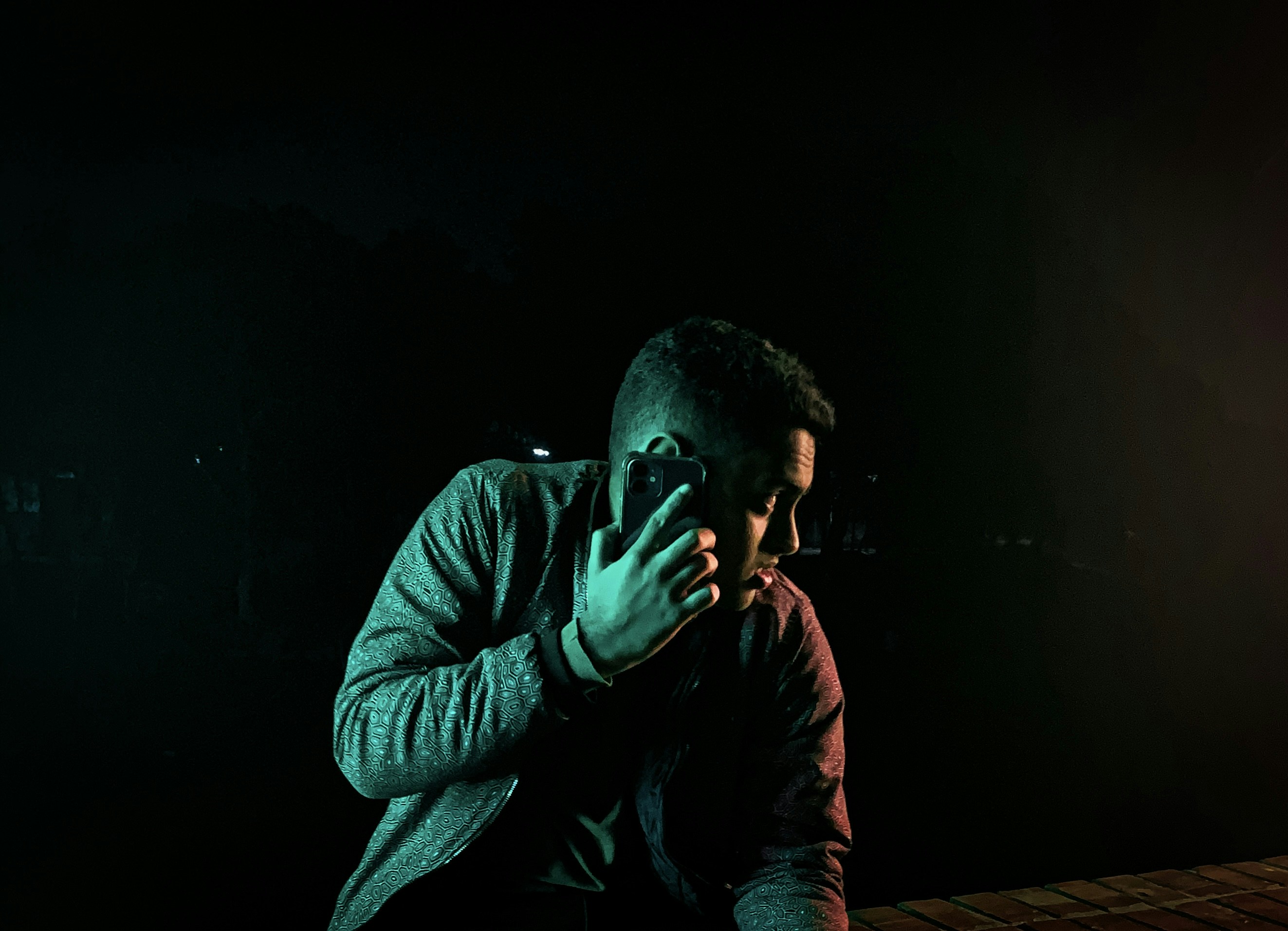 Man illuminated by moody, cinematic lighting making a phone call