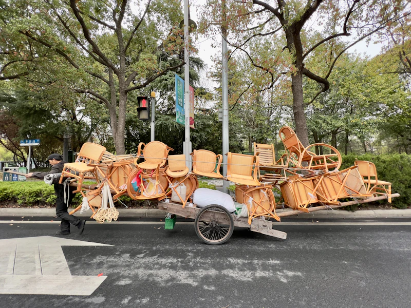 Cart stacked impossibly high with wicker chairs on a city street