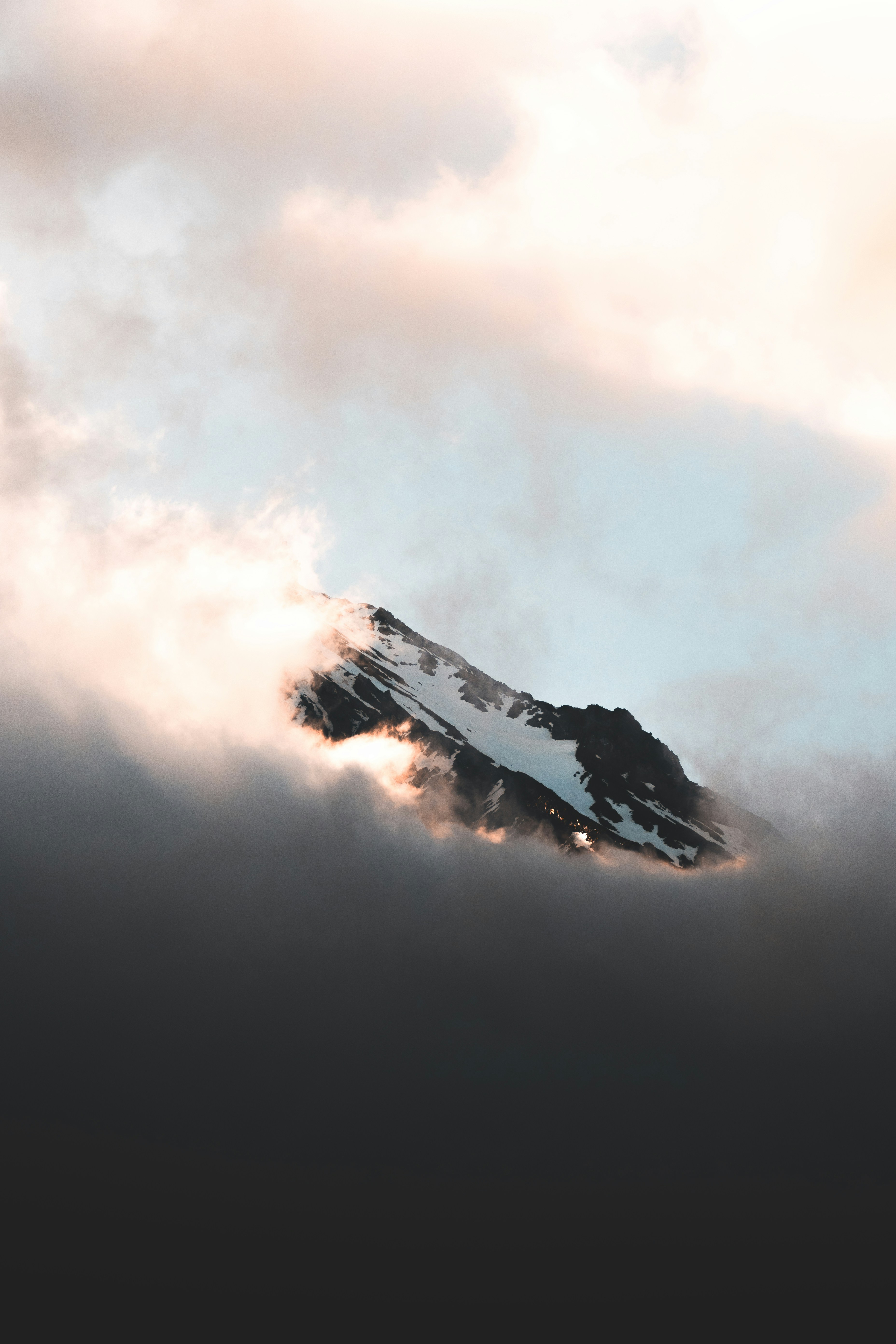 Mountain peak peeks through the clouds at sunset