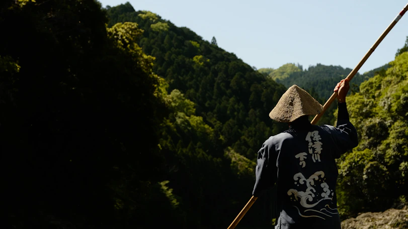 A man paddles through a river with scenic views.