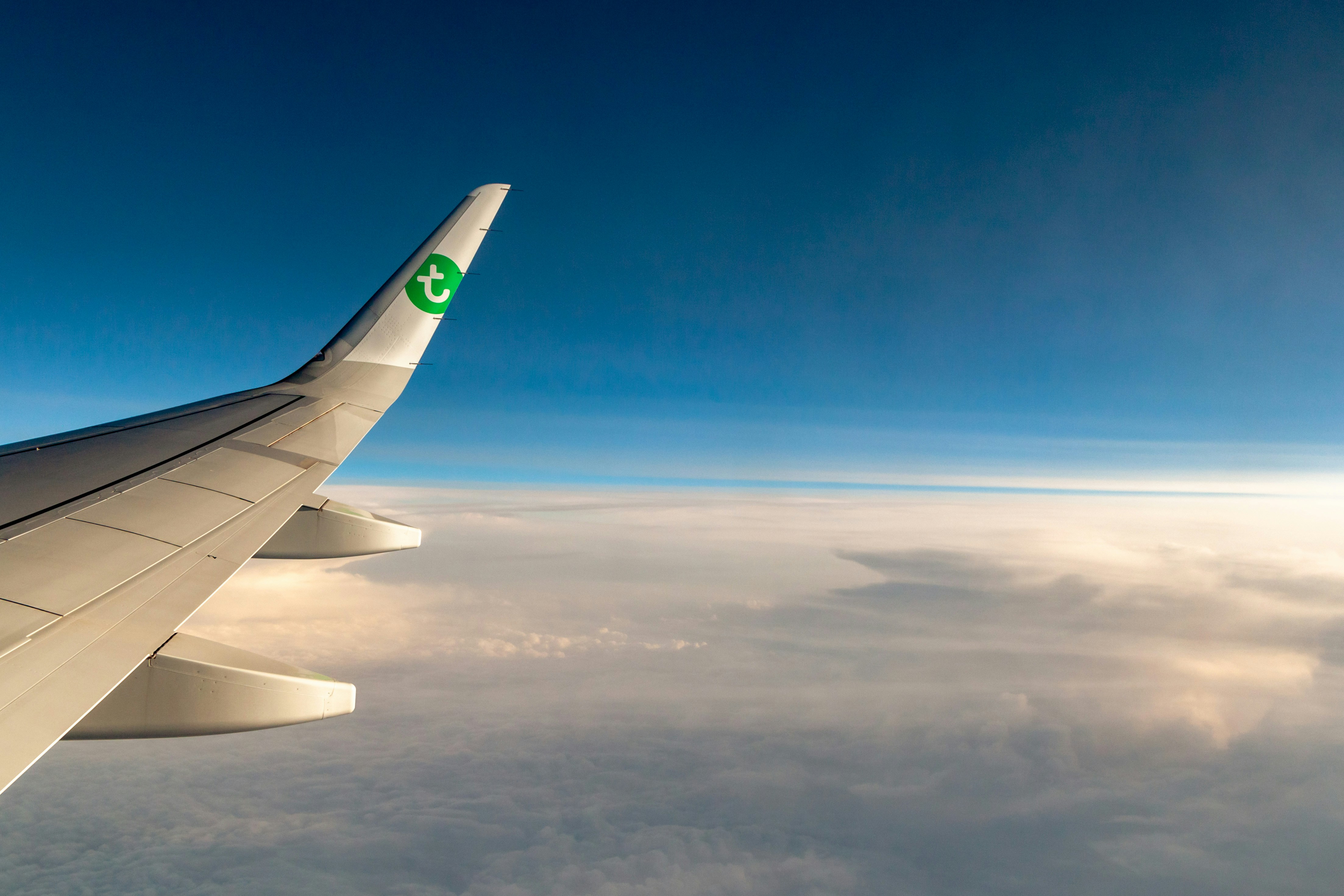Airplane wing flying above the clouds in the sky.